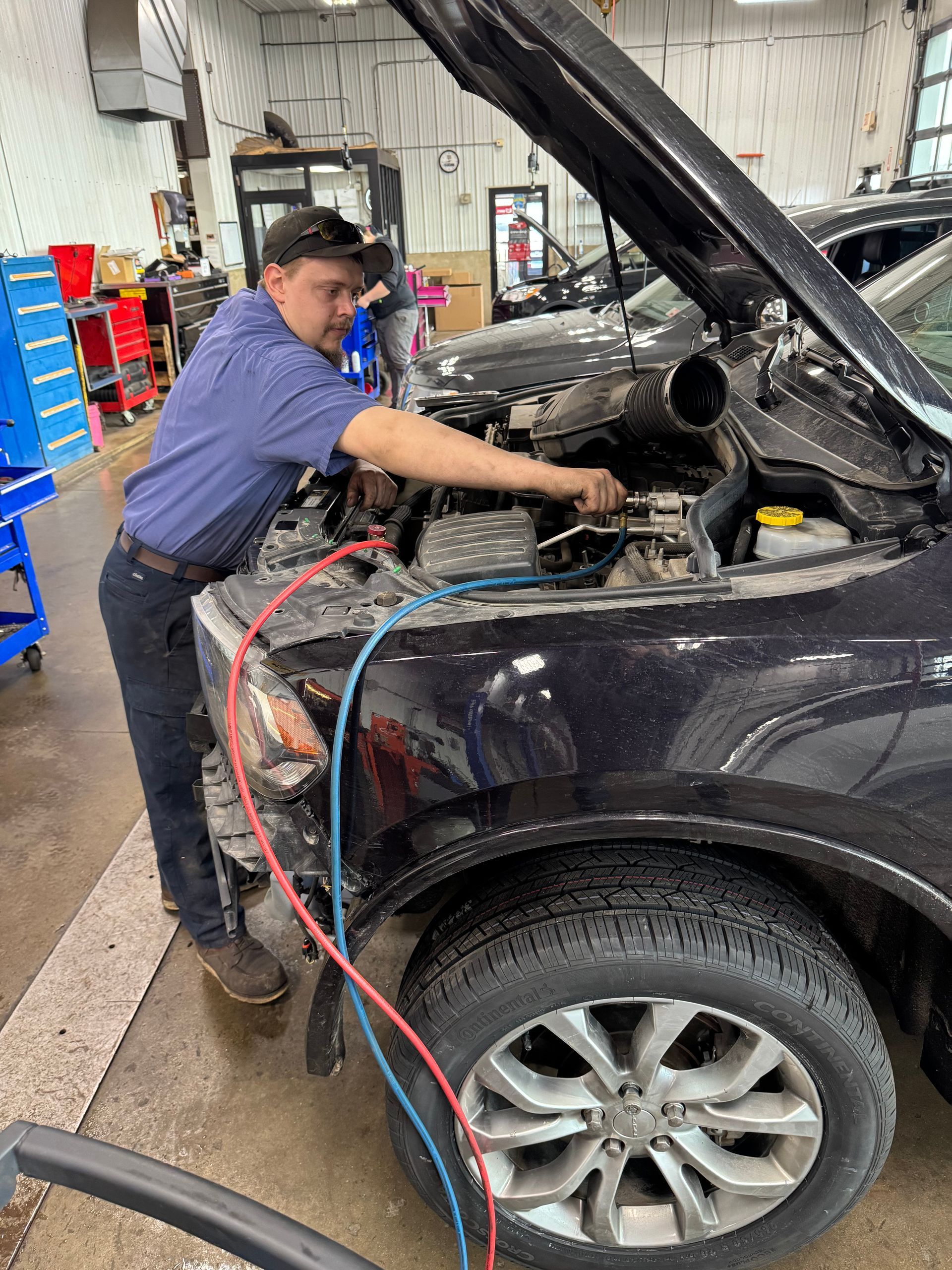 A man is working on the engine of a car in a garage.