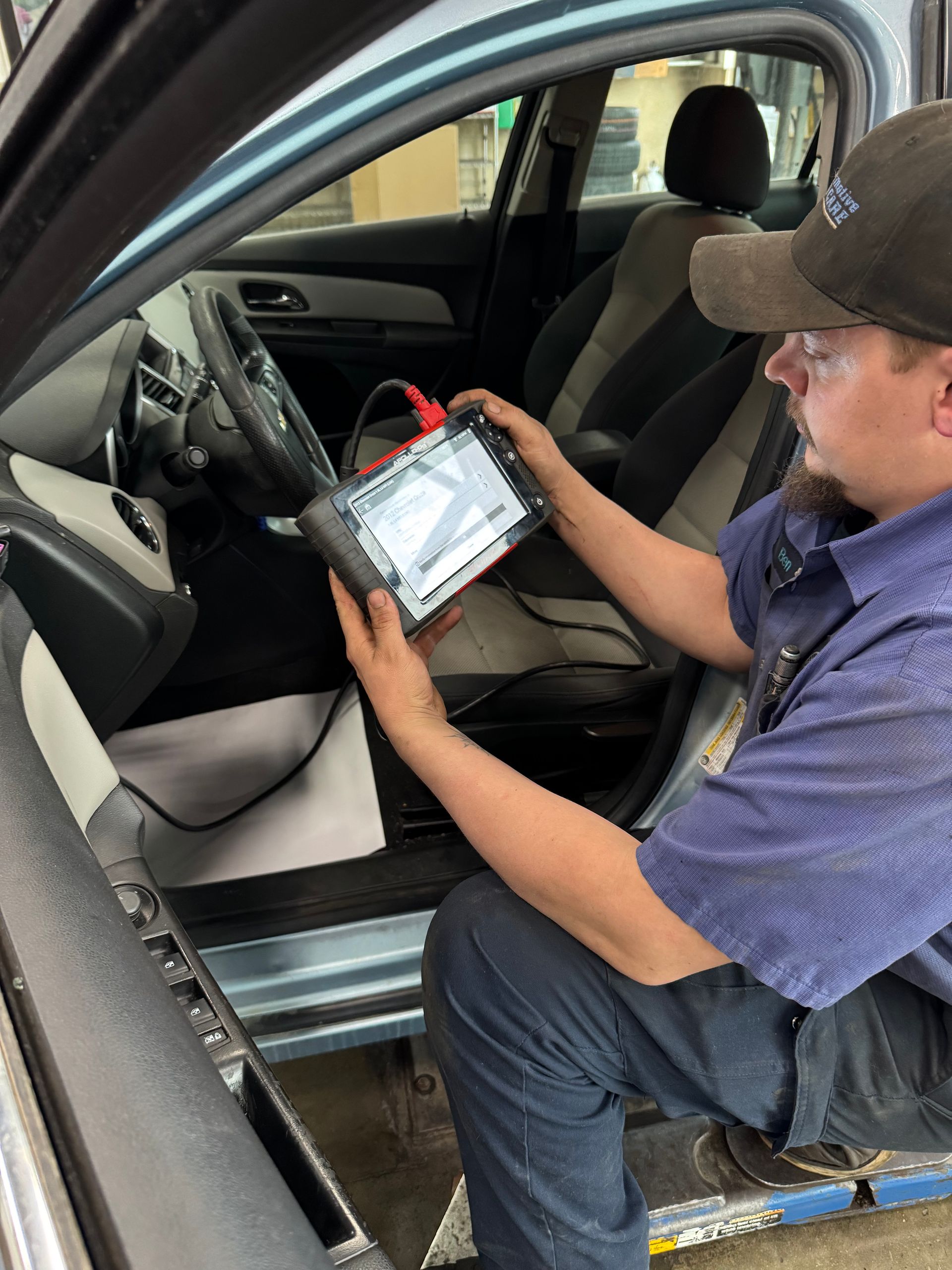 A man is sitting in a car looking at a tablet.