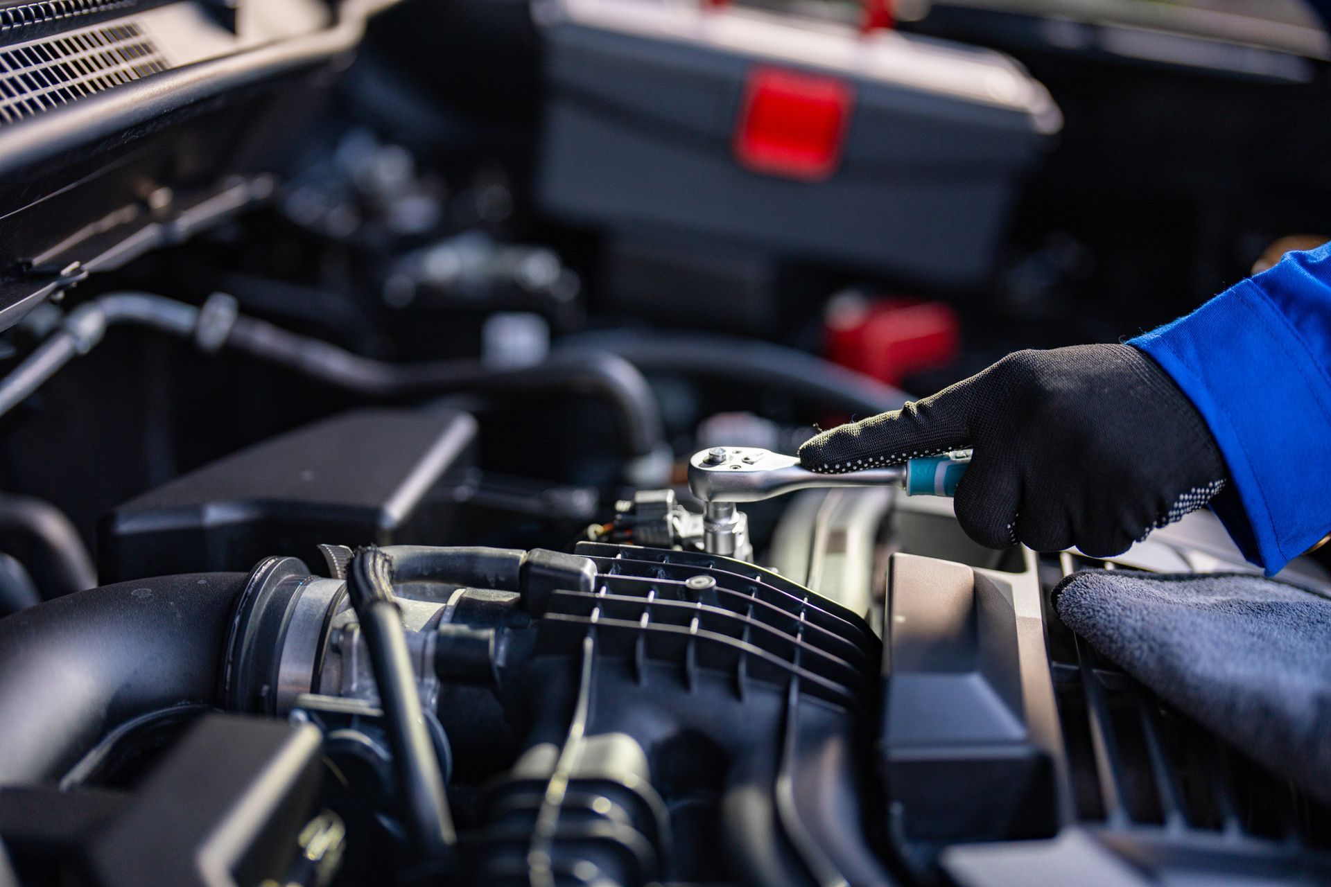 A mechanic is working on a car engine with a wrench.