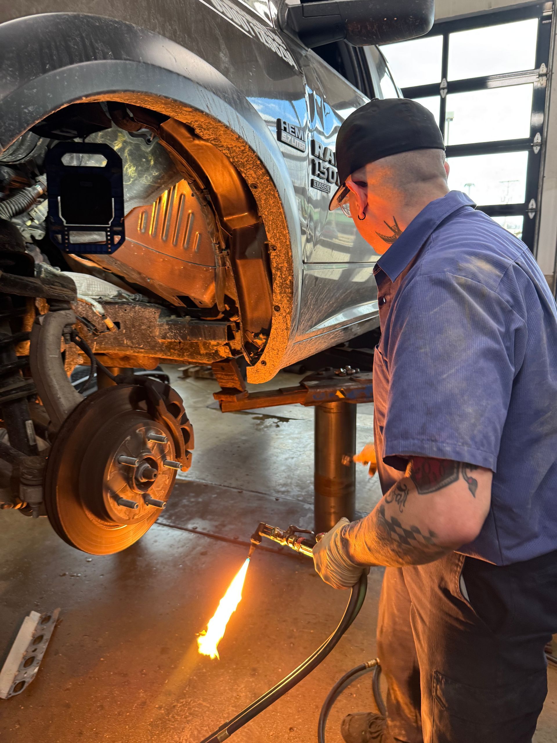 A man is welding a car with a torch in a garage.