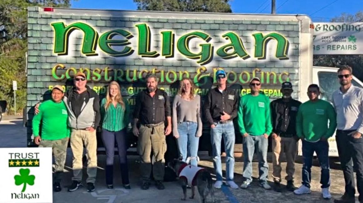 A group of Neligan team members are posing for a picture in front of their truck.