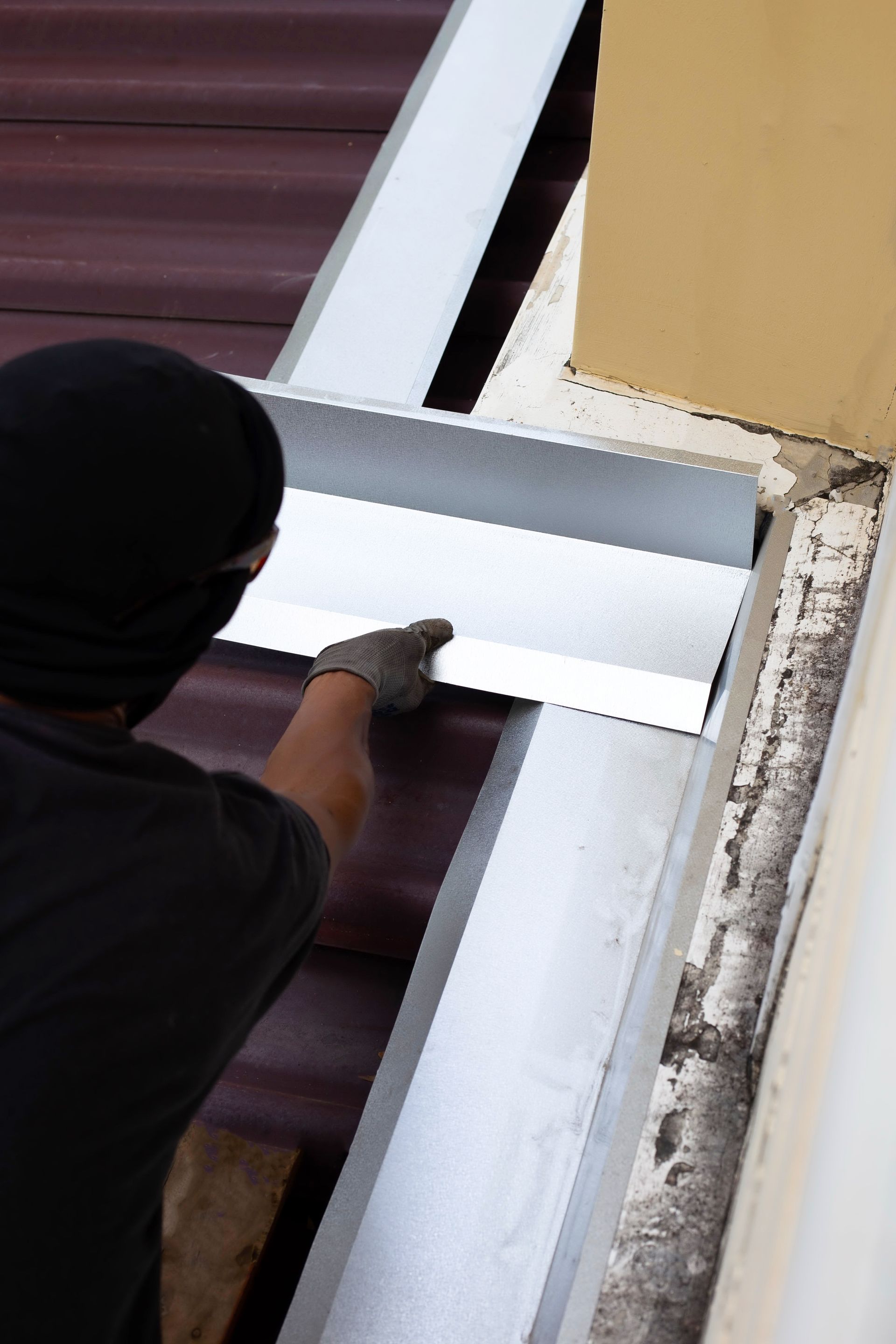 A man is working on a gutter on a roof.