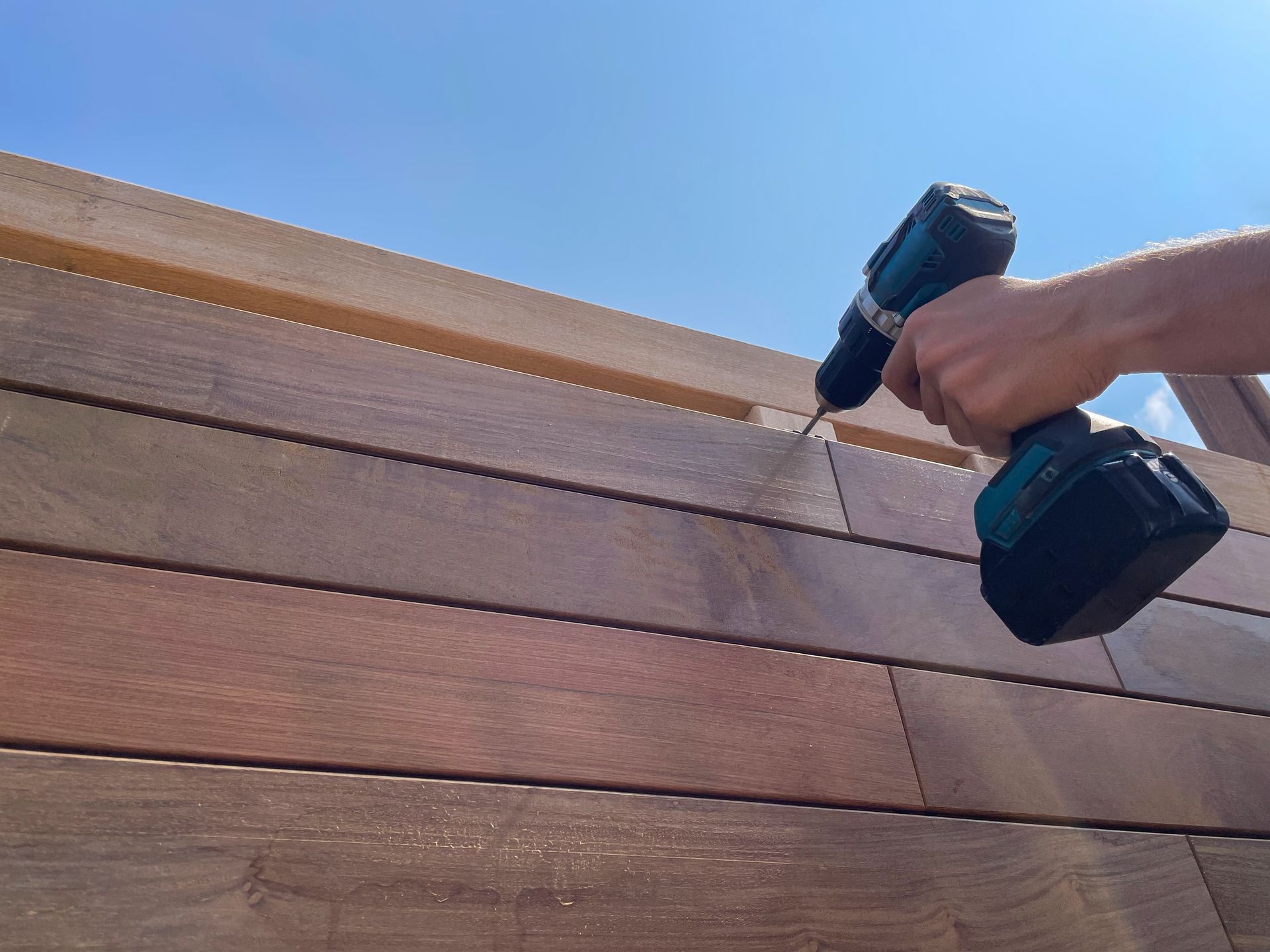 A person is using a drill on a wooden wall