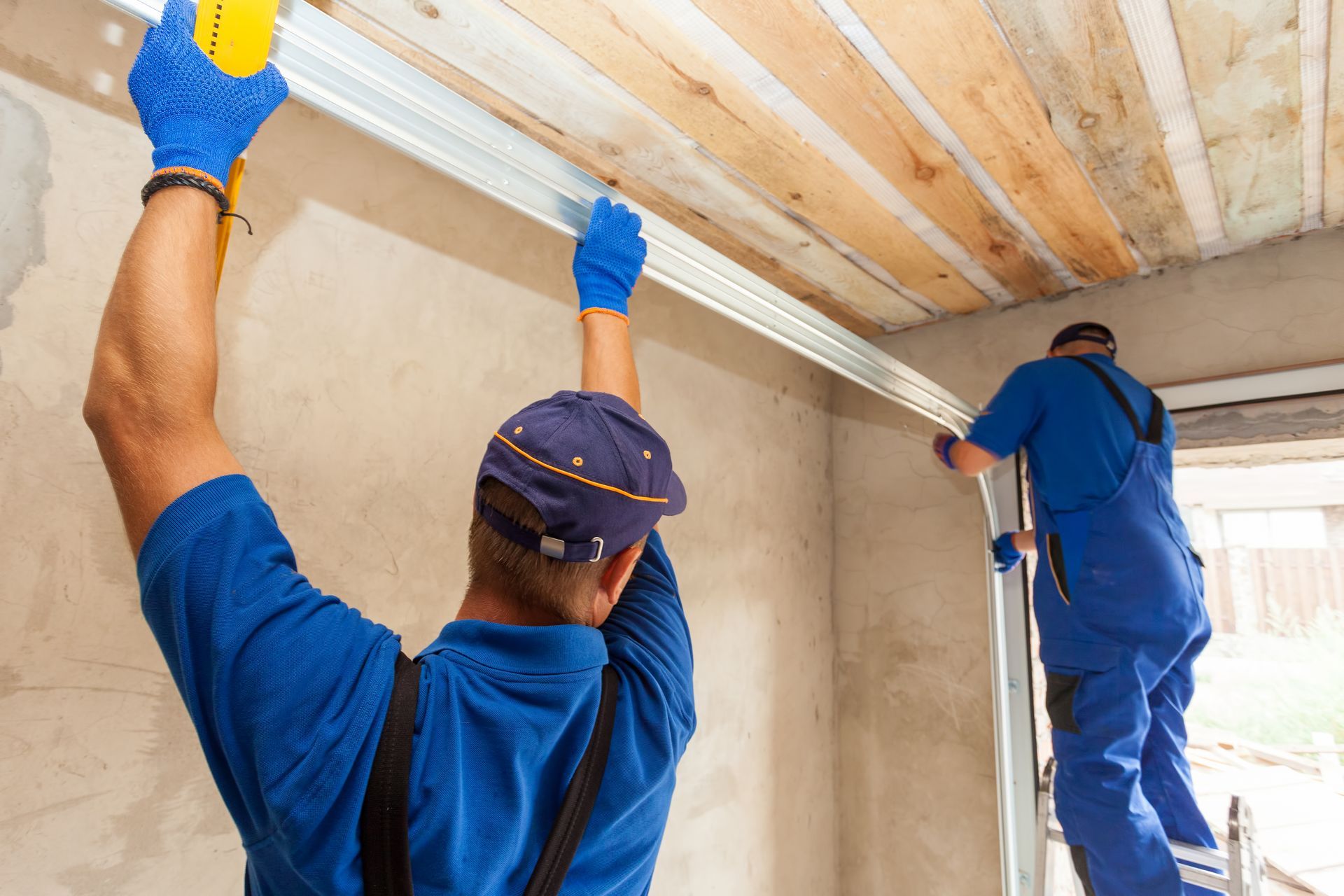 Two men are working on a garage door.