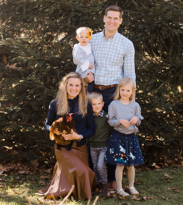 Family portrait with parents and three children; woman holding chicken.