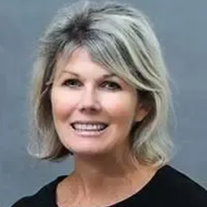 Woman with short gray hair, smiling, wearing a black shirt.