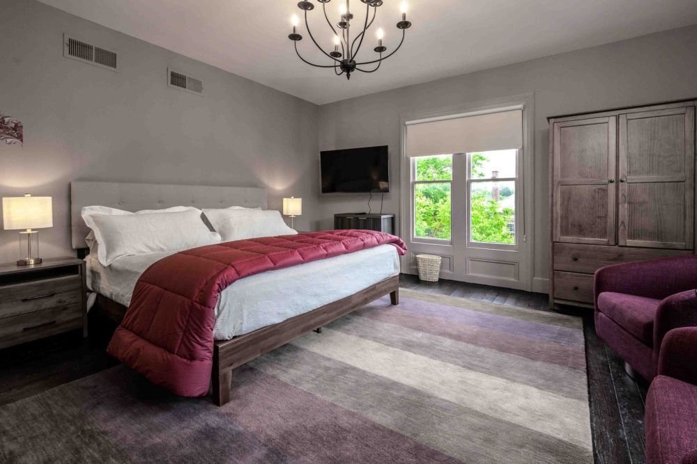 Bedroom with a king bed, purple accents, and a large window.