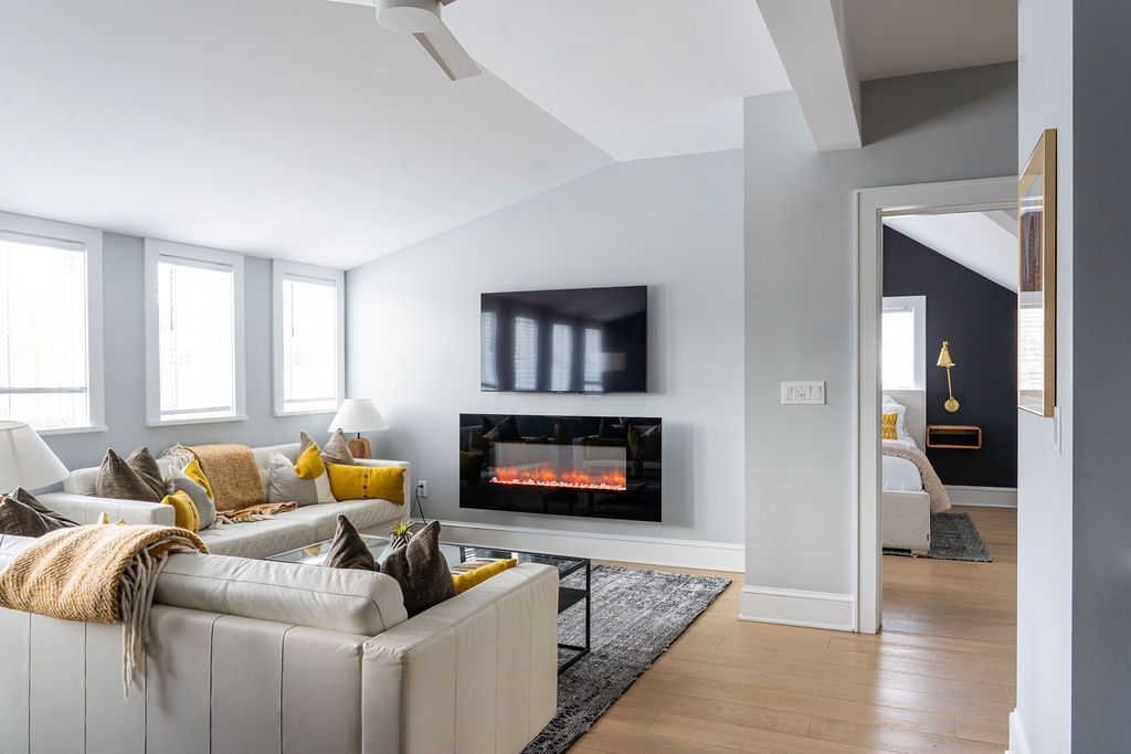 Modern living room with white sofas, dining table, and dark accent wall.