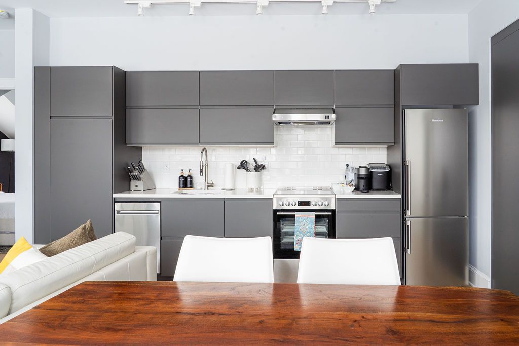 Modern gray kitchen with stainless steel appliances and white countertops.