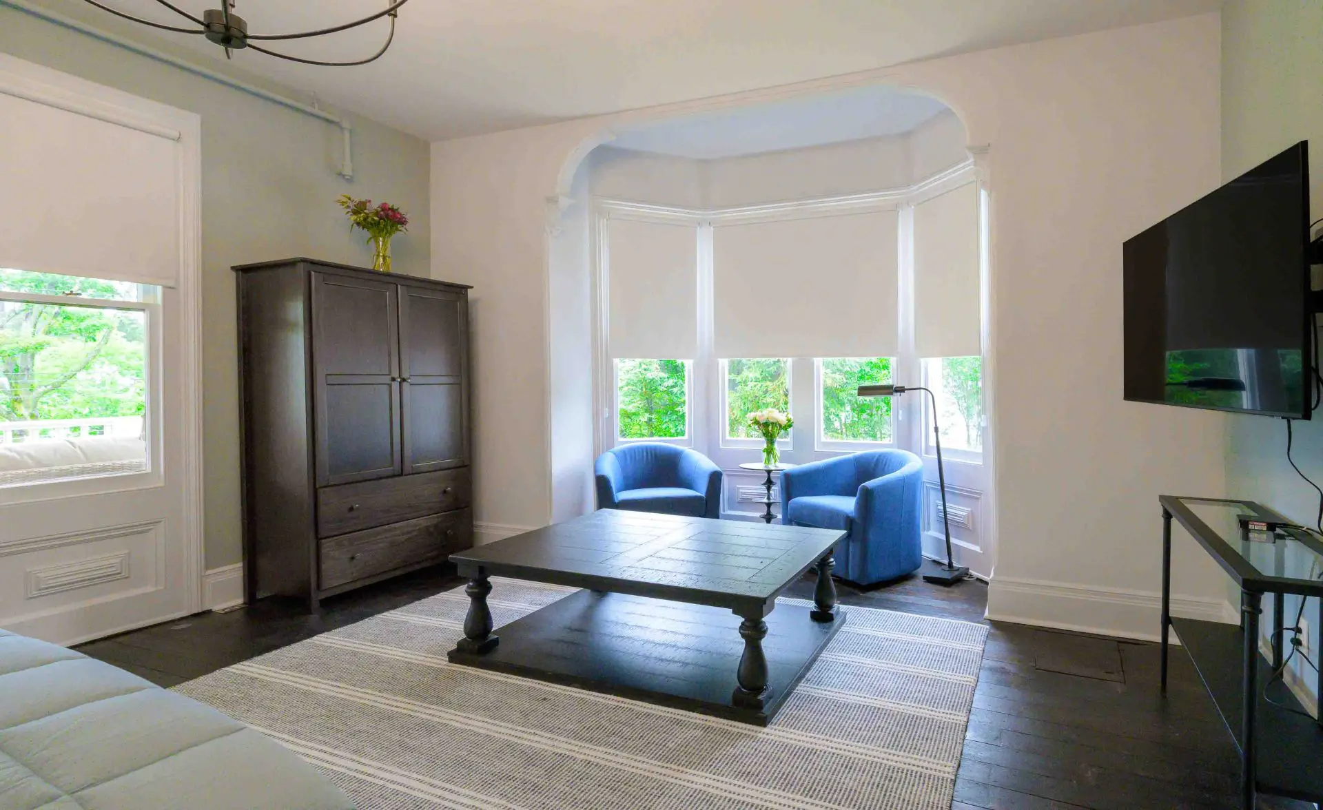 Living room with dark wood furniture, blue chairs, and a large window.