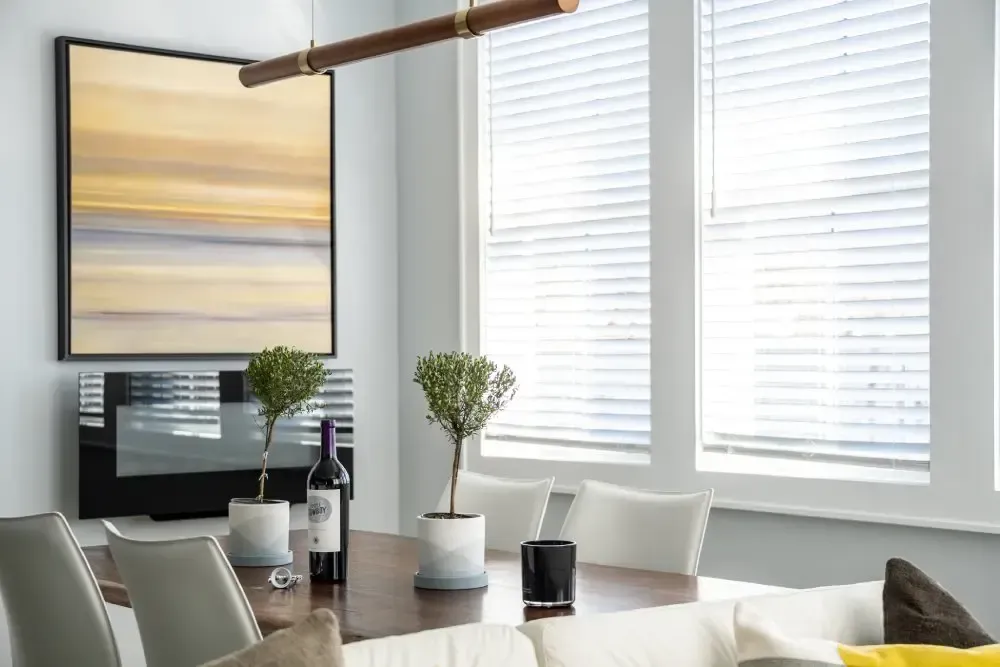 Dining room with a table, art, windows, and plants.