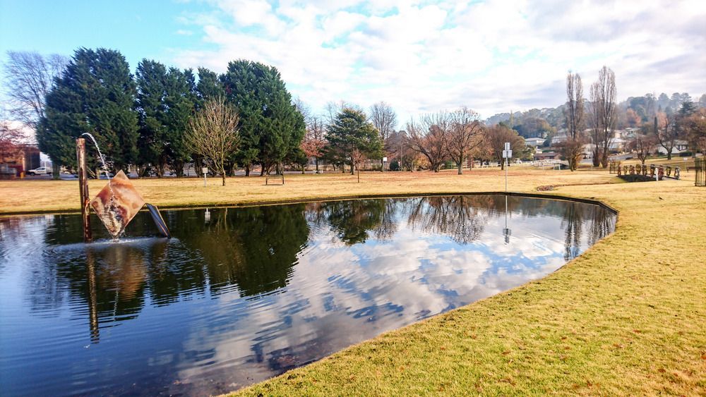 A Pond in A Park with A Statue in The Middle of It — Podium Solar in Armidale, NSW