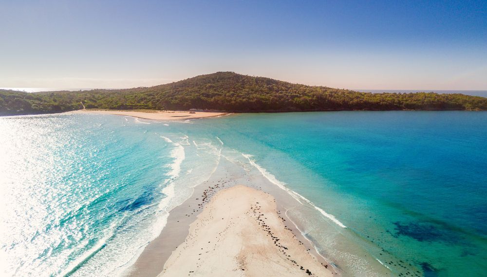 An Aerial View of A Beach with A Small Island in The Middle of The Ocean — Podium Solar in Port Stephens, NSW