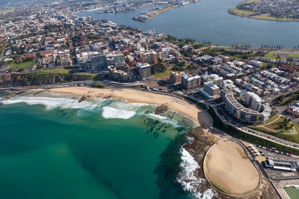 An Aerial View of A City Surrounded by Water and A Beach — Podium Solar in Newcastle, NSW