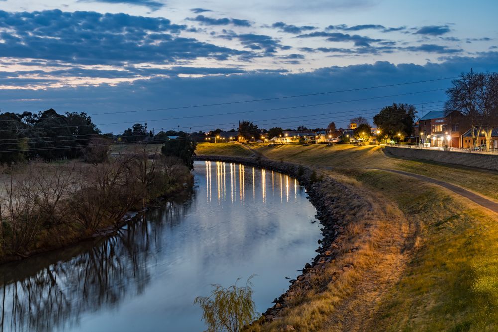 A River Runs Through a City at Night with Lights Reflected in The Water — Podium Solar in Maitland, NSW