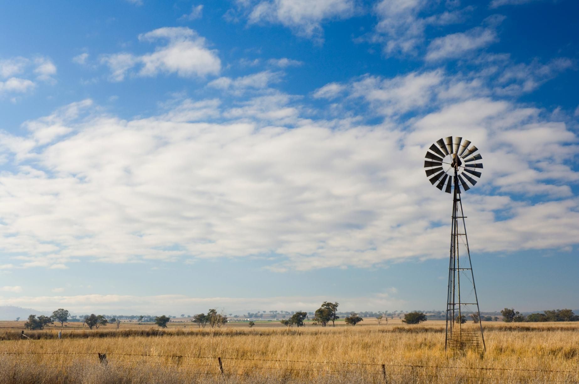 A Windmill in The Middle of A Field with A Blue Sky in The Background — Podium Solar in Valentine, NSW