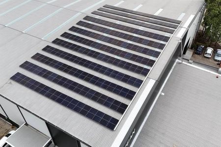 A Row of Solar Panels on Top of A Building with A City Skyline in The Background — Podium Solar in Cameron Park, NSW