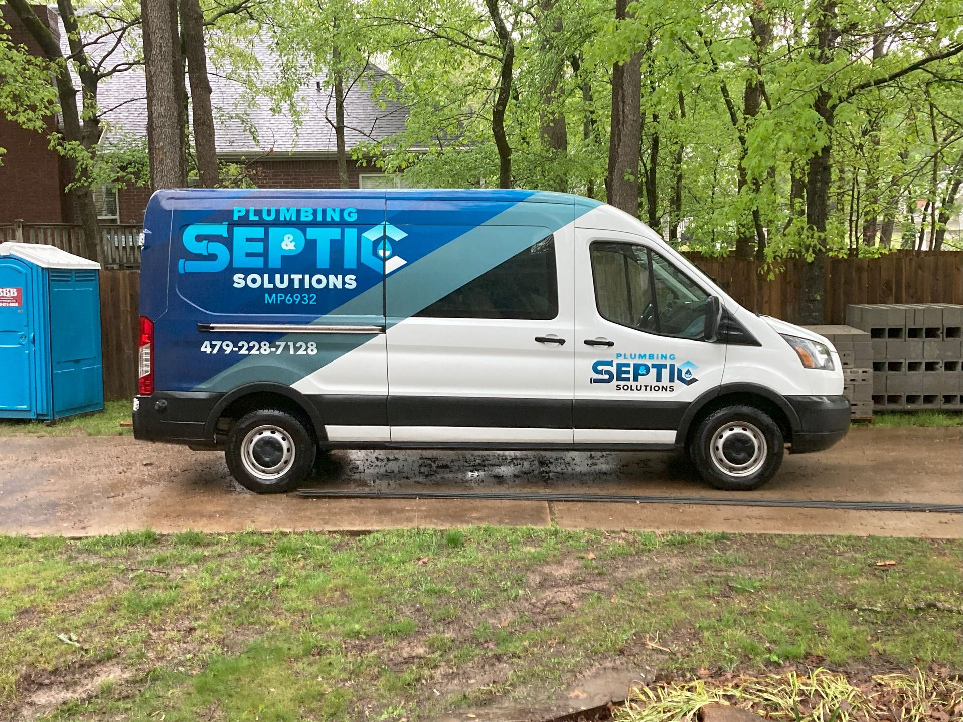 A white and blue septic solutions van is parked in a driveway.