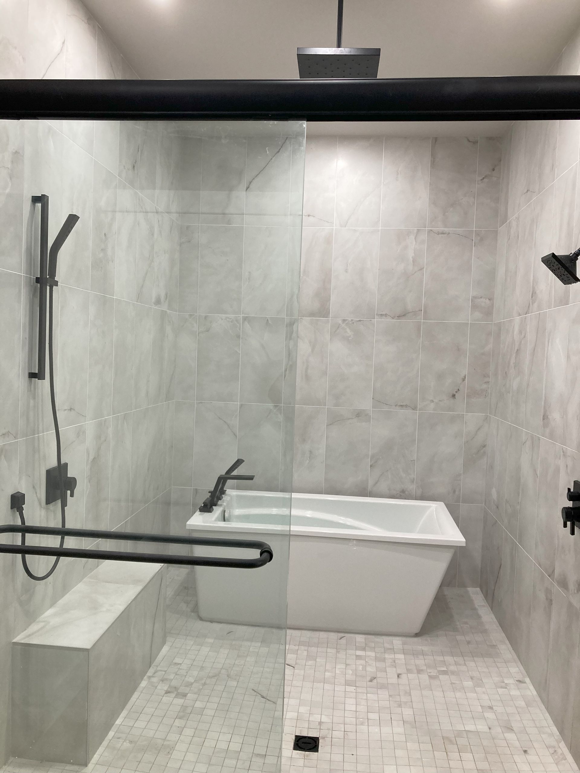 A bathroom with a tub and a shower with a glass door.