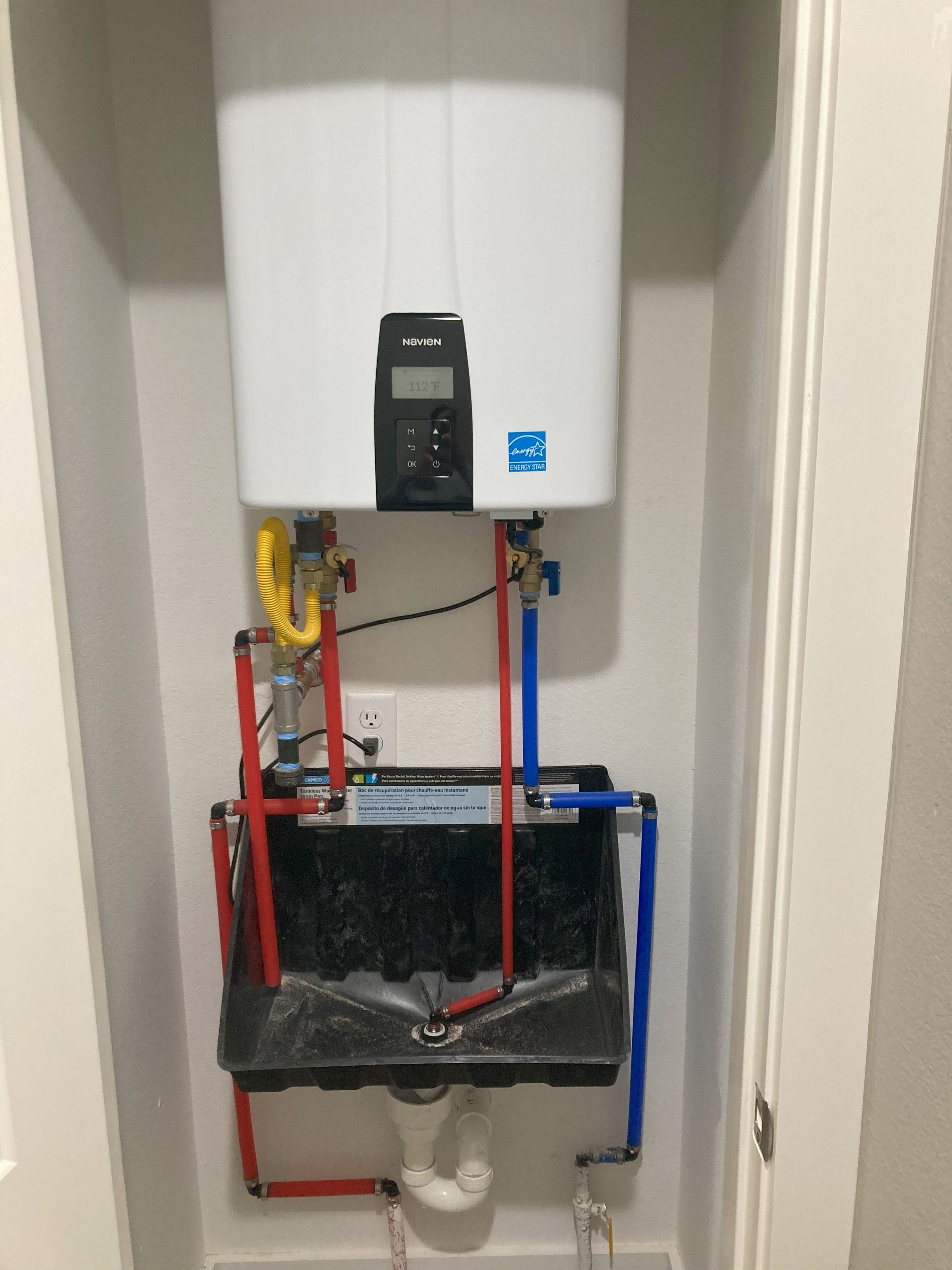 A white water heater is mounted to the wall above a sink.
