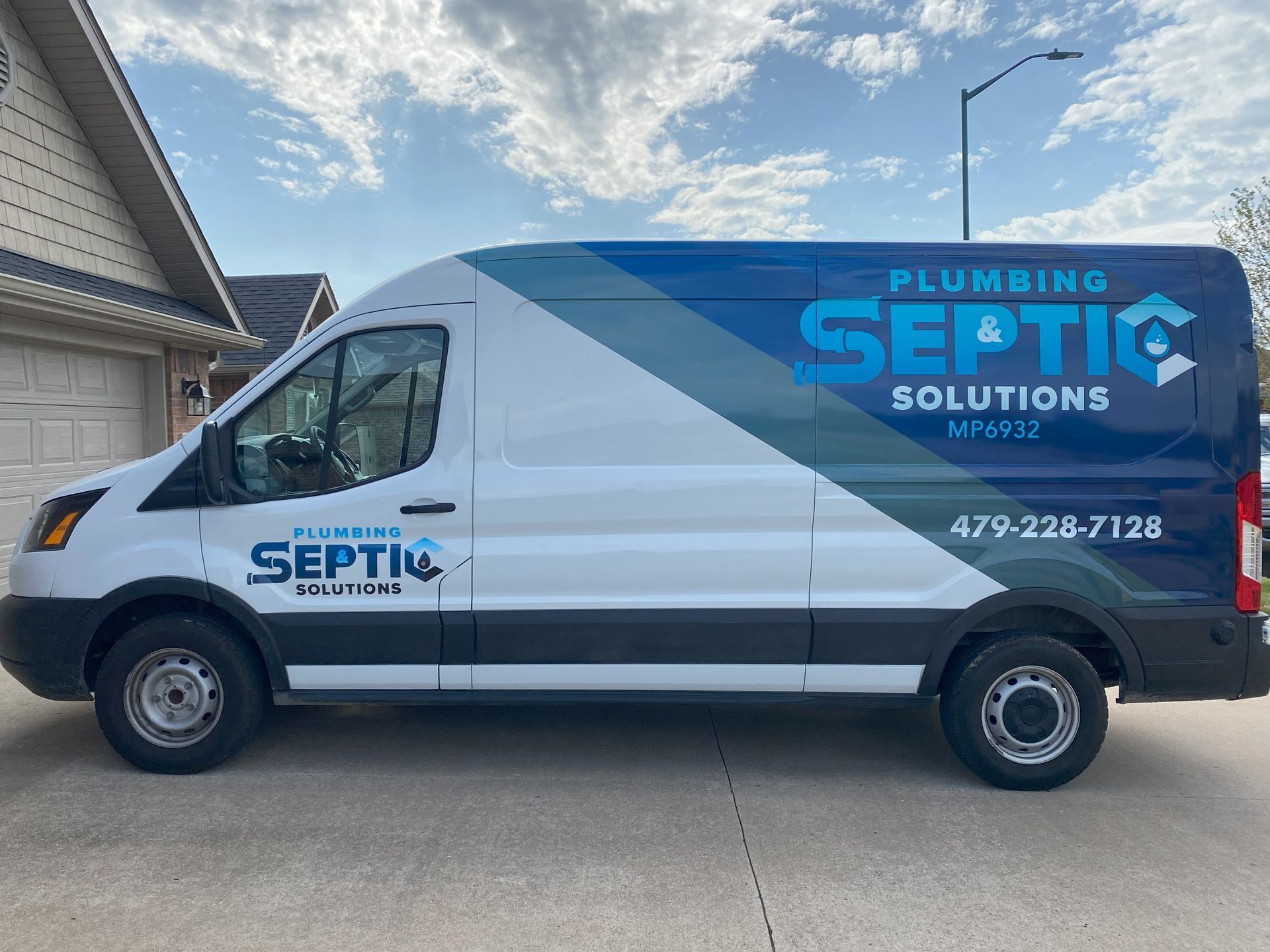 A white and blue van is parked in front of a house.