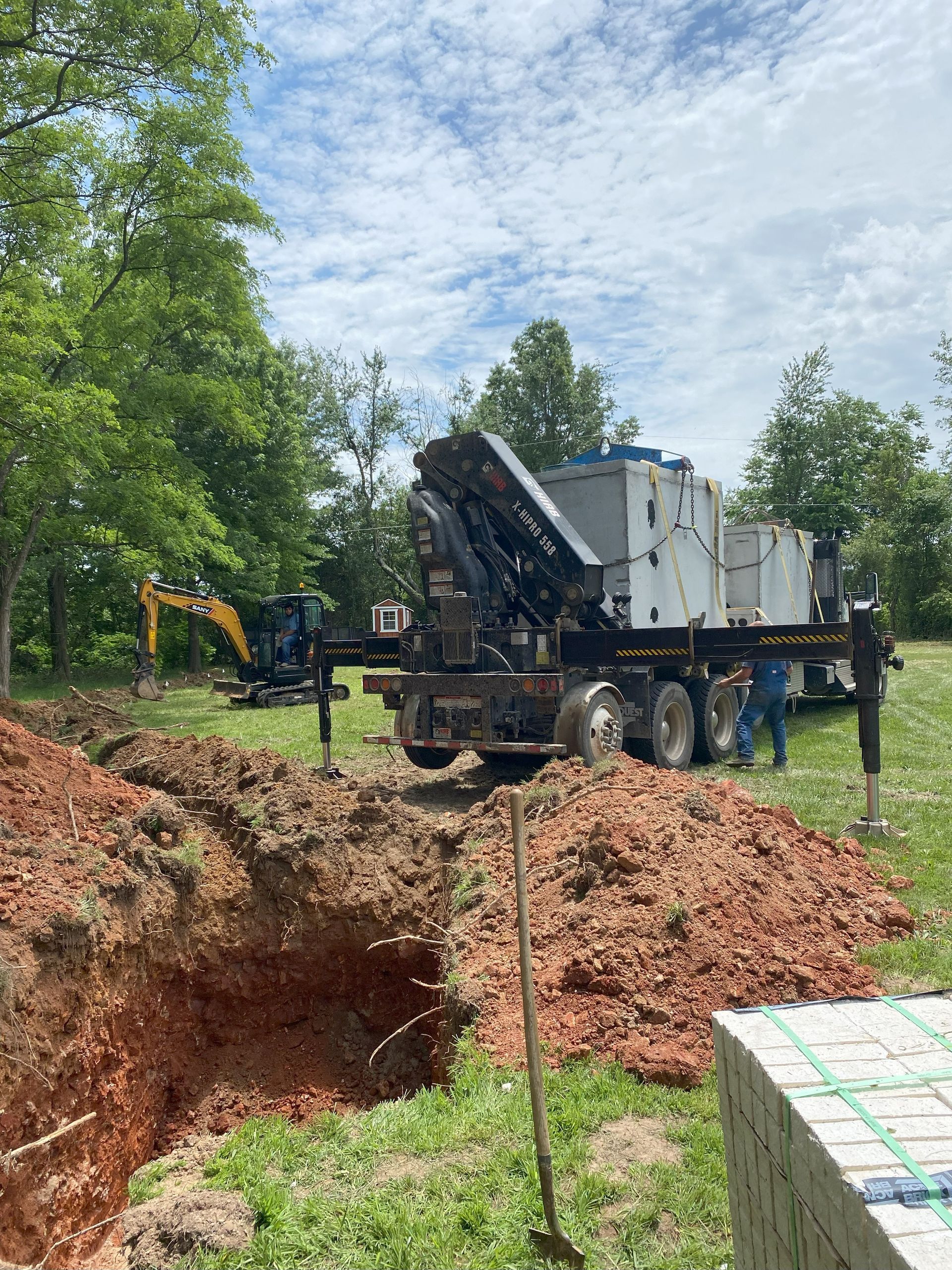 A truck is digging a hole in the ground in a field.