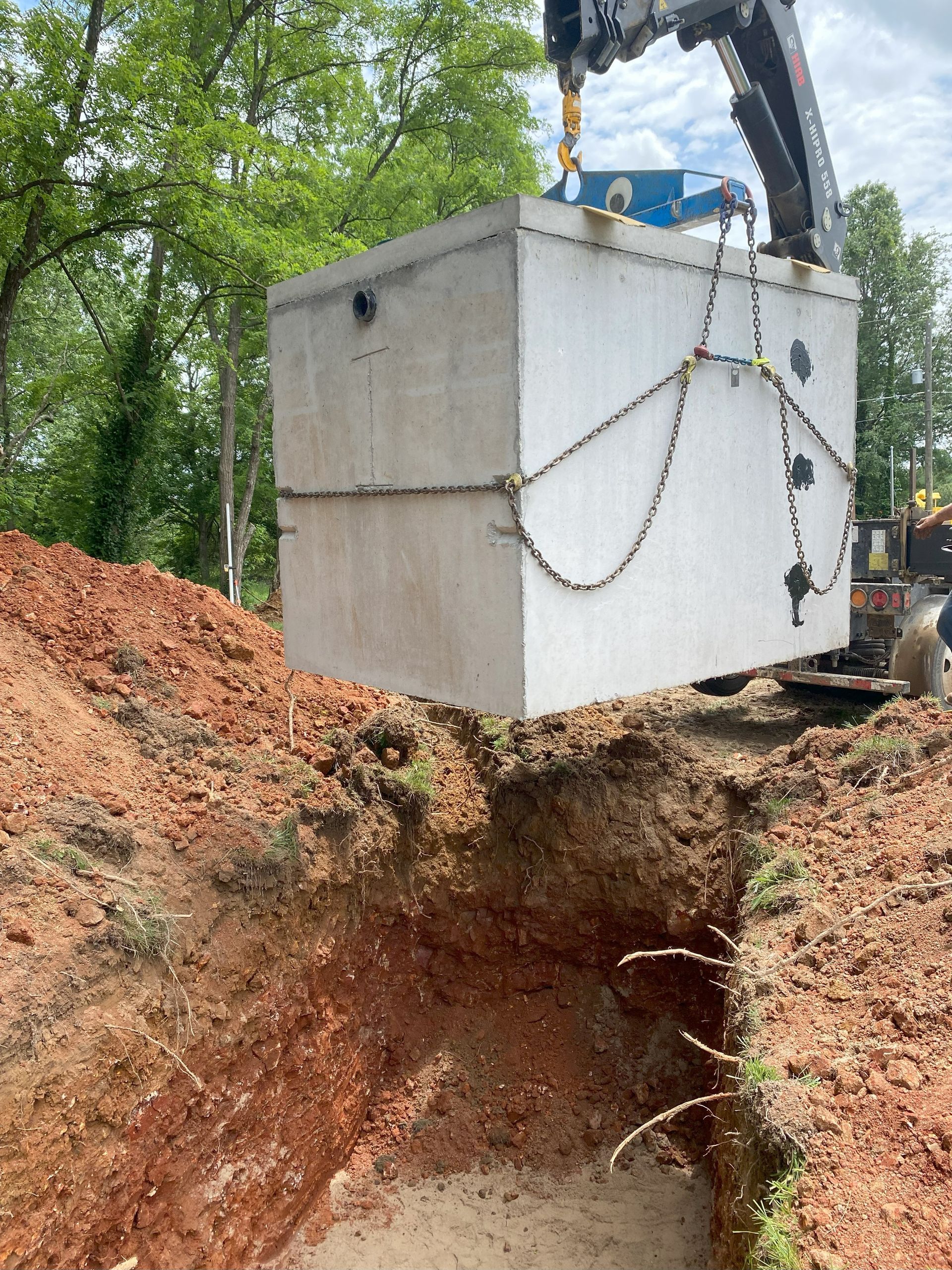 A large white box is being lifted out of the ground by a crane.