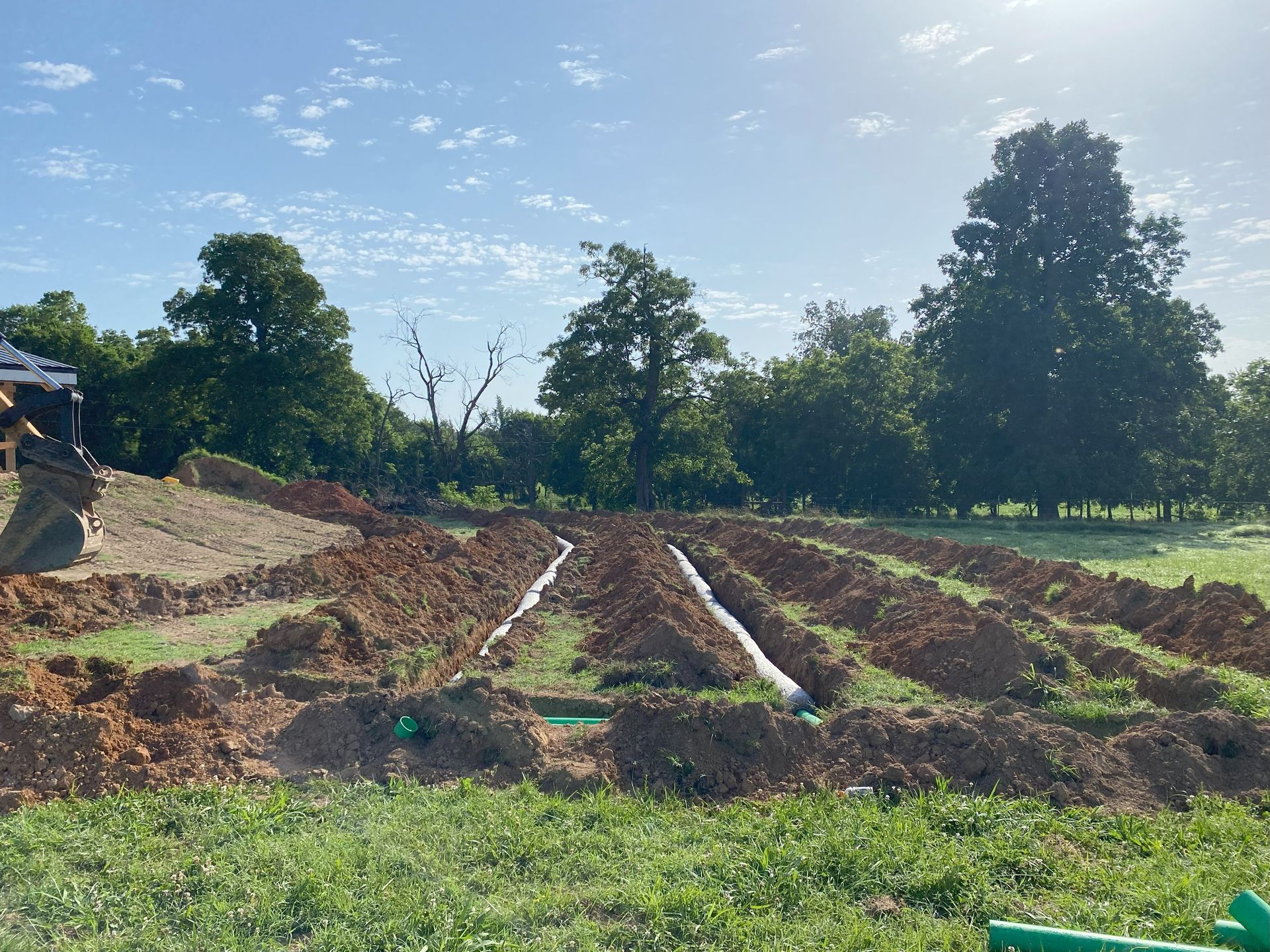 A construction site with a bulldozer and pipes in the dirt.