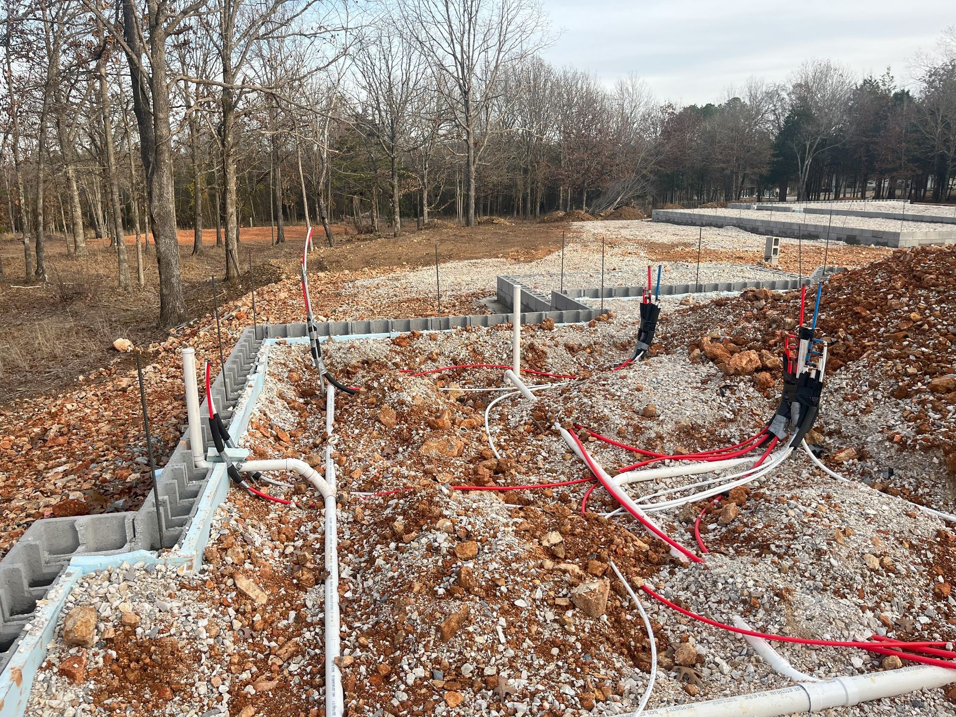 A construction site with a lot of pipes and trees in the background.
