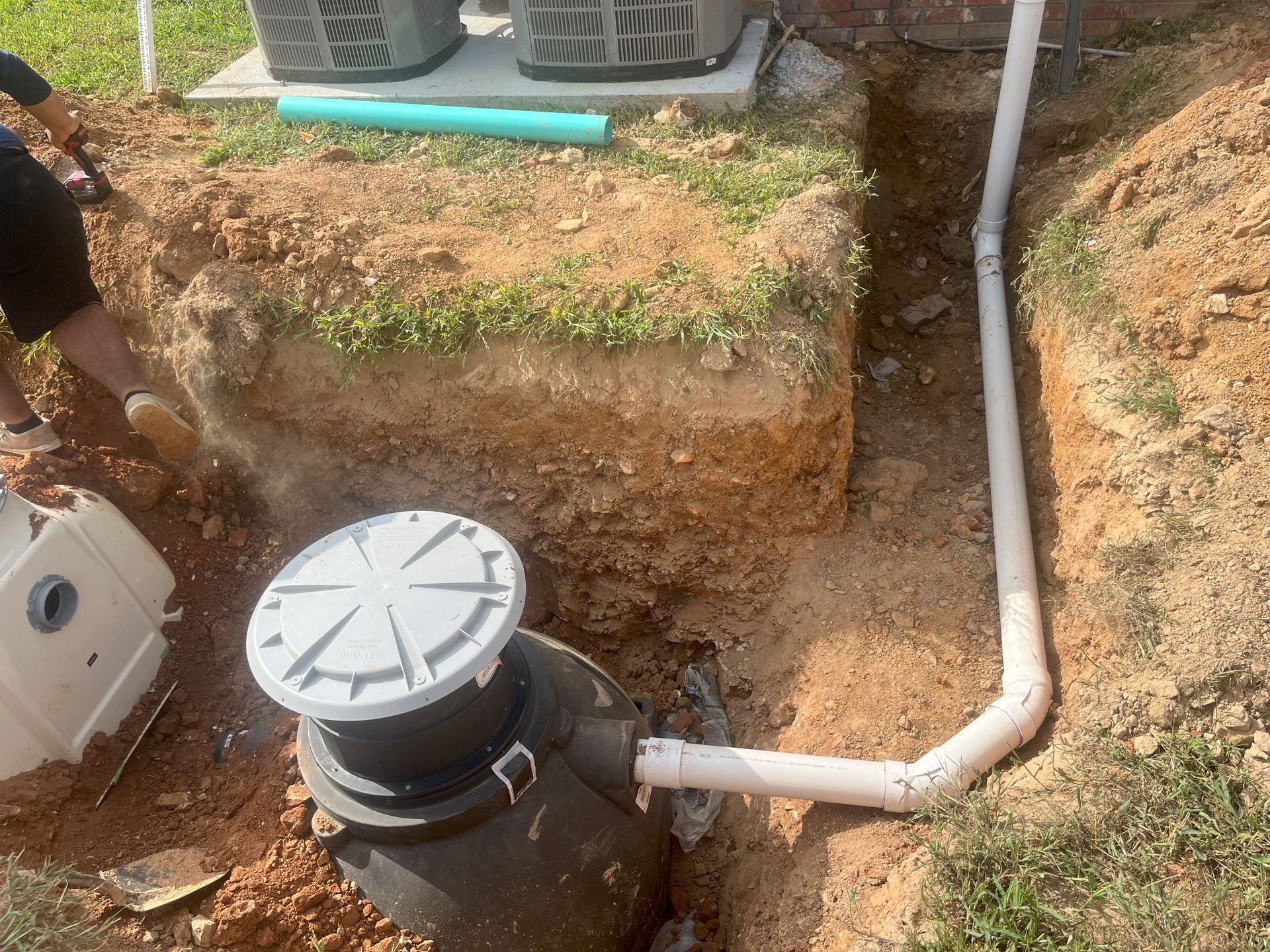 A man is digging a hole in the ground to install a septic tank.