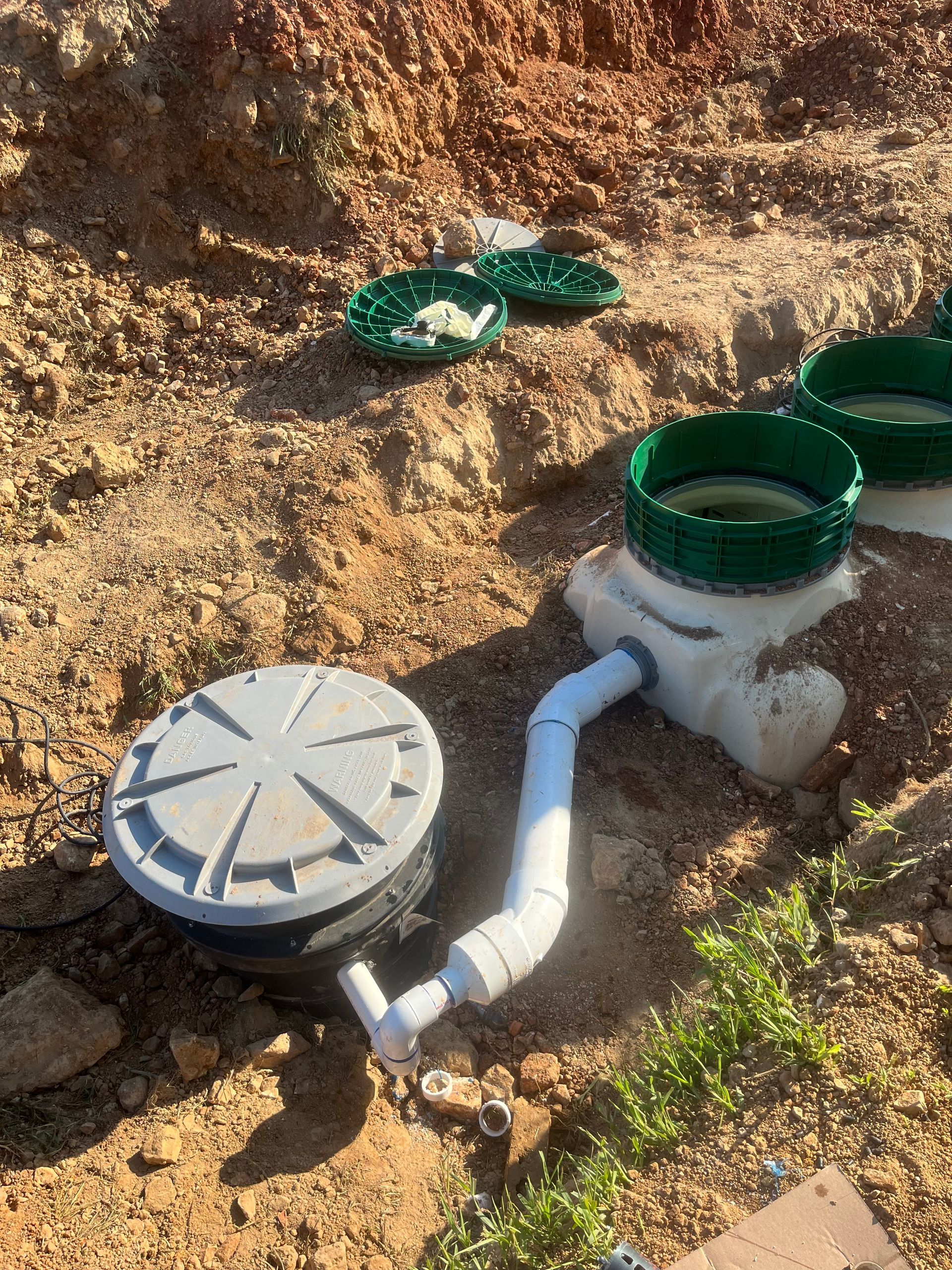 A septic tank is sitting in the dirt next to a pipe.