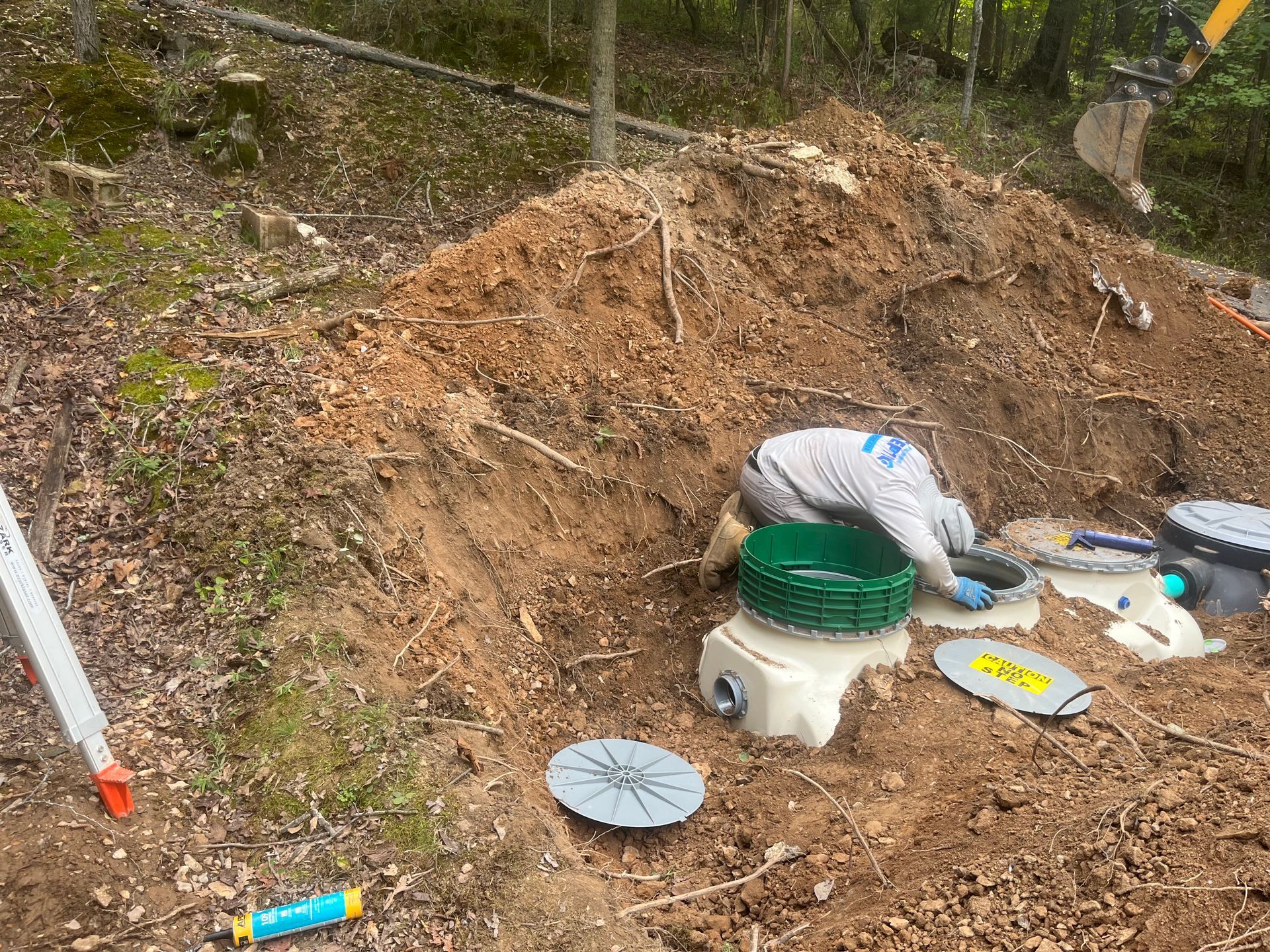 A man is kneeling in the dirt next to a pile of dirt.