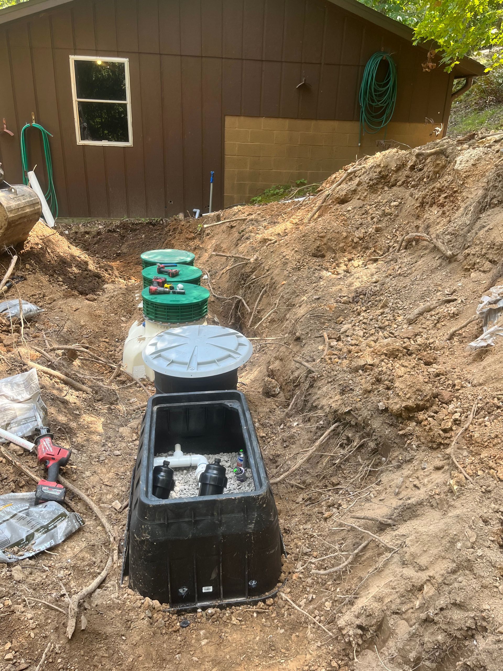 A septic tank is sitting in the dirt in front of a house.