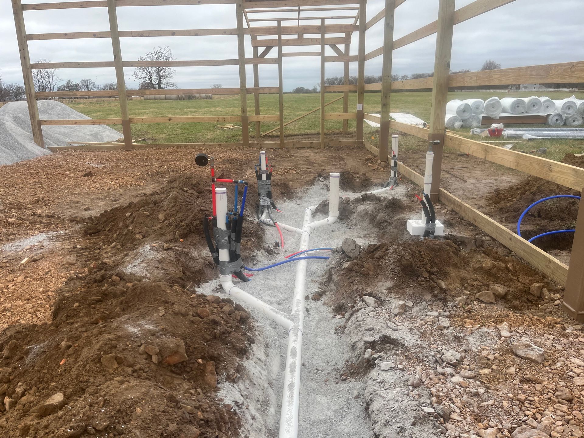 A pipe is being installed in the dirt next to a wooden fence.