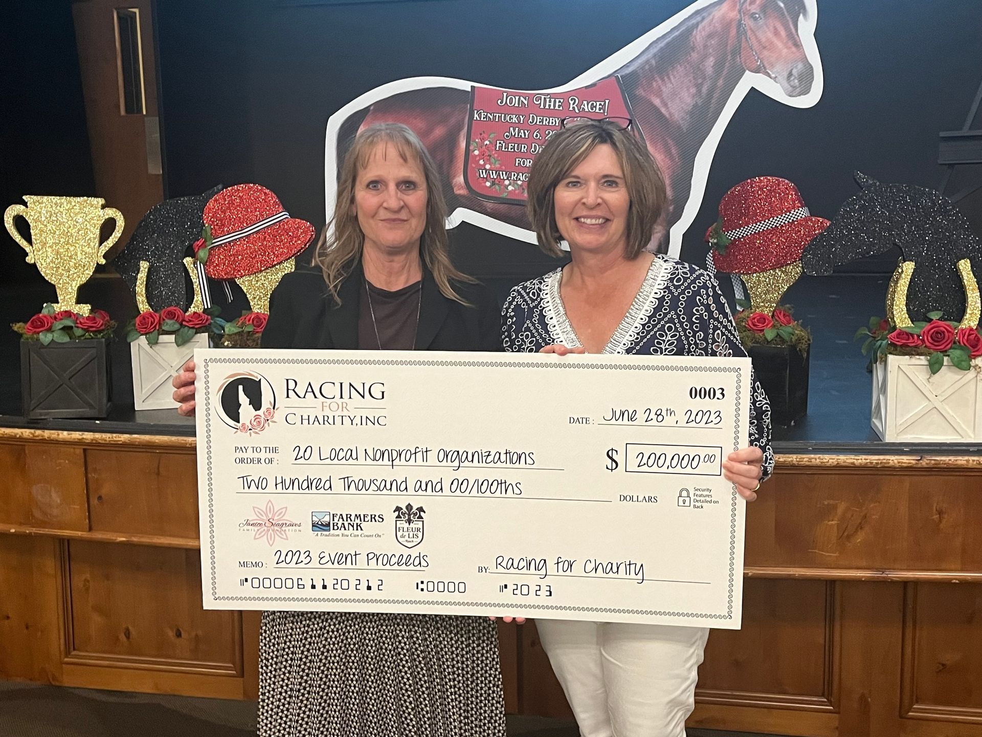 Two women are holding a large check.