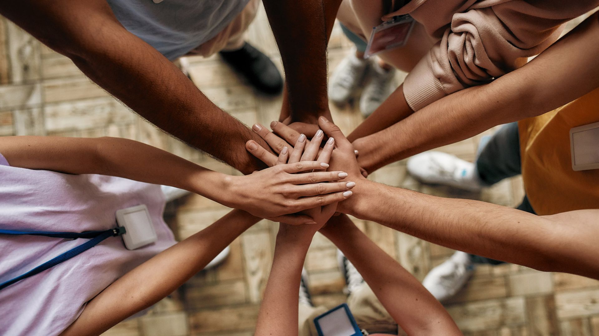 A group of people are putting their hands together in a circle.