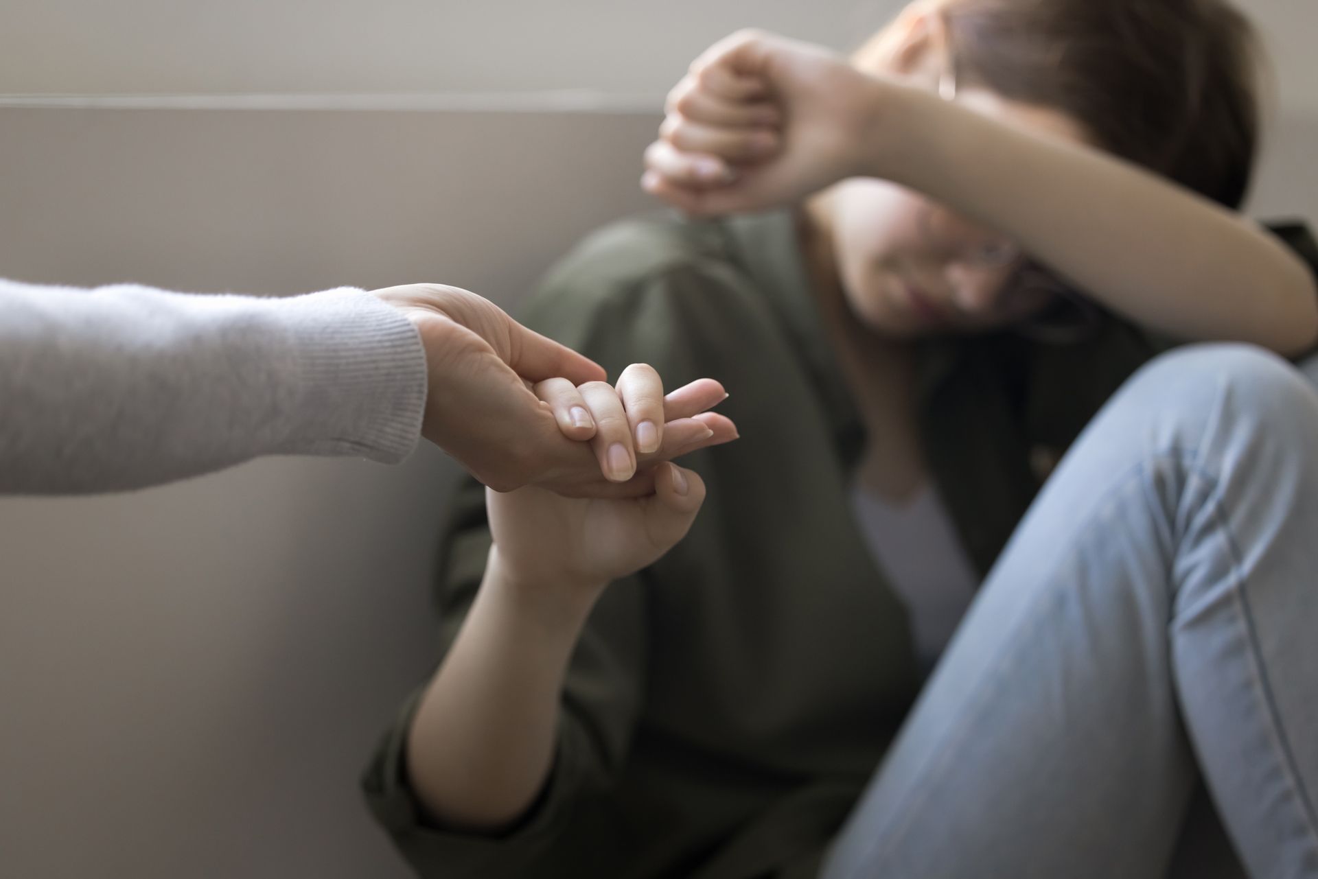 A woman is sitting on the floor holding another woman 's hand.