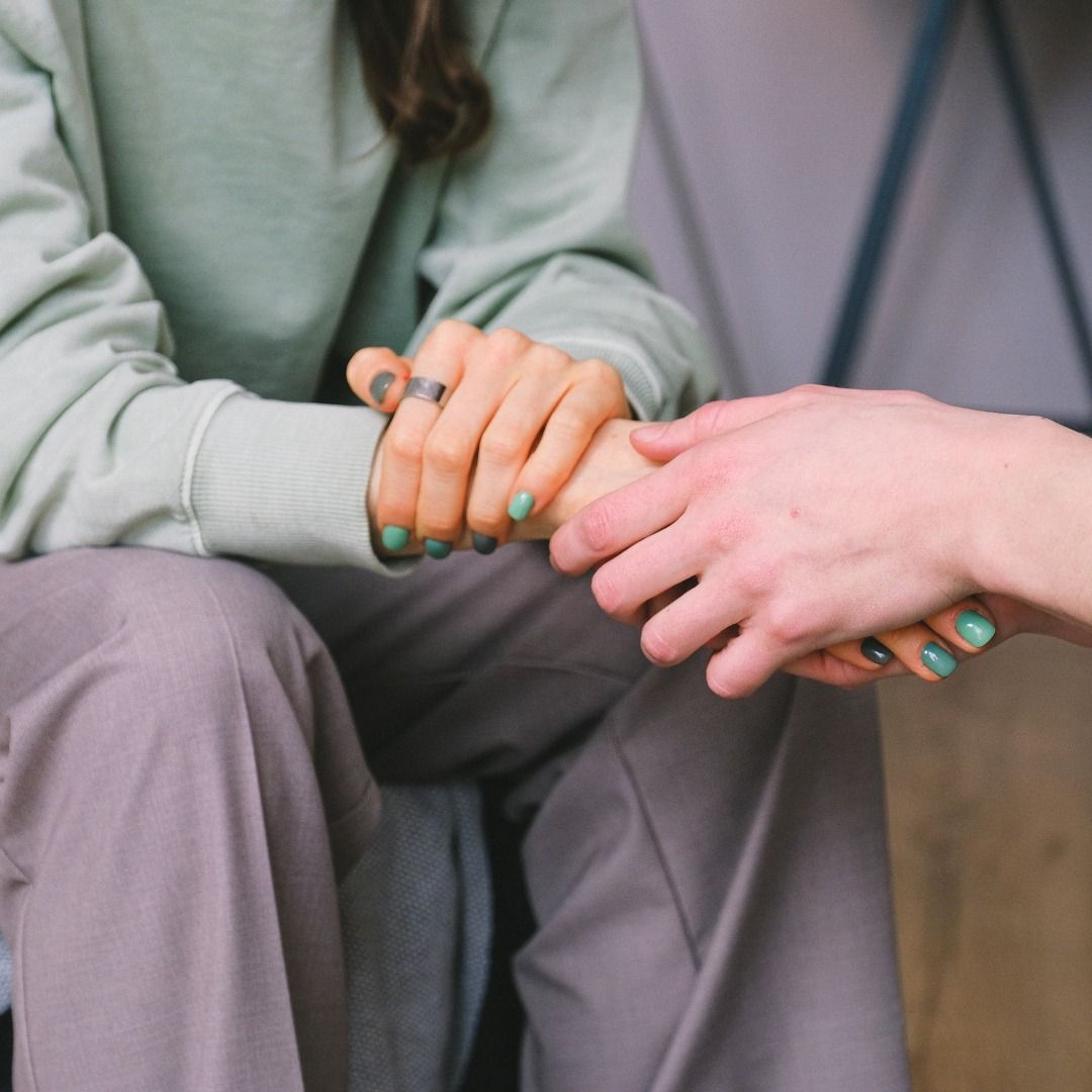 A woman with green nails is holding a man 's hand