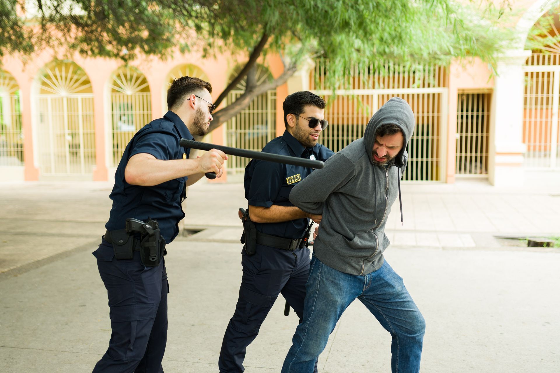 Person in jeans and blue shirt, hands cuffed behind their back.