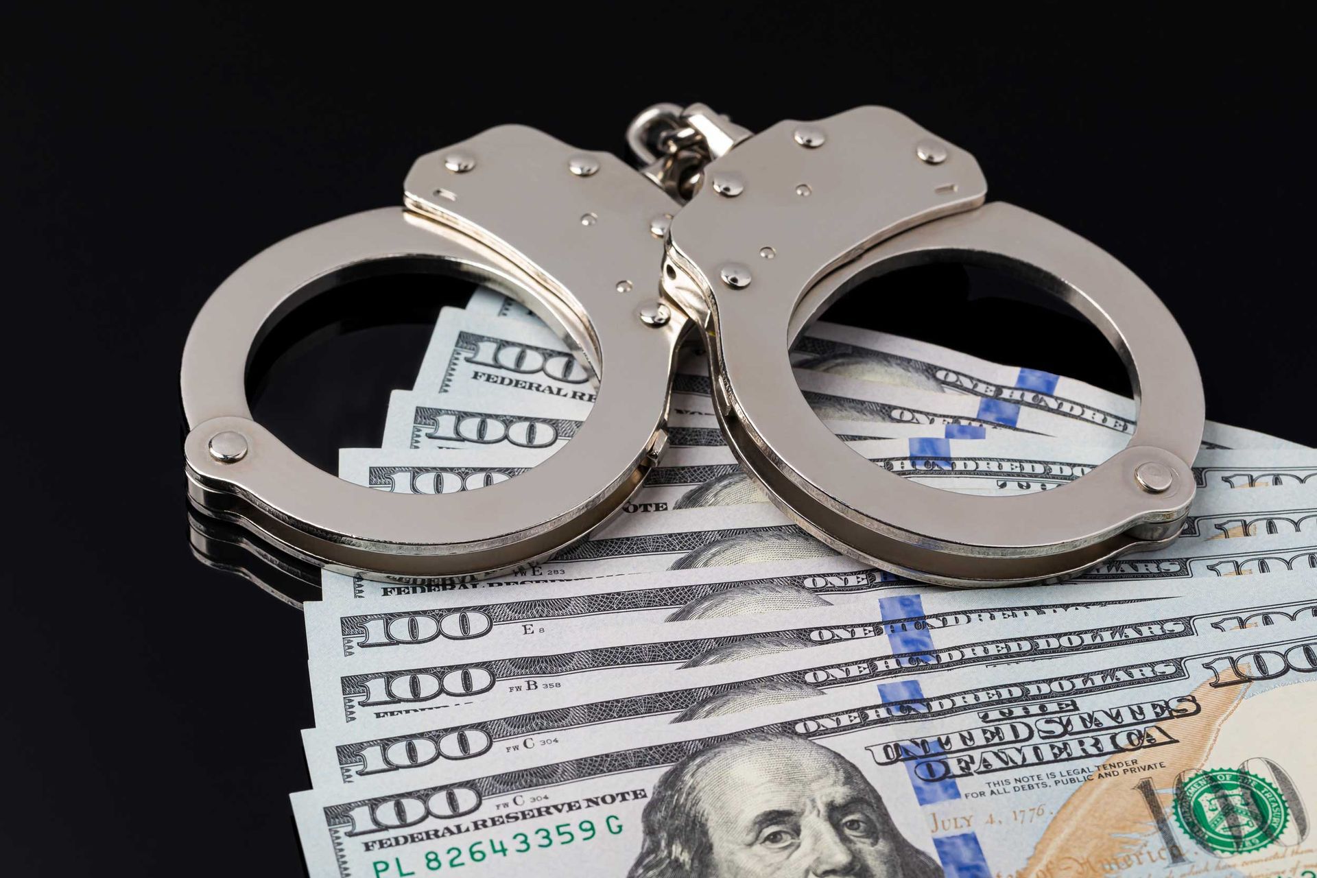 Handcuffs lying on a stack of US dollar bills