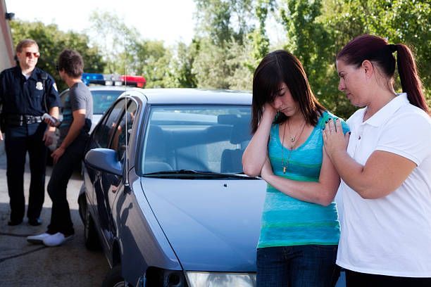 Two women are standing in front of a police car