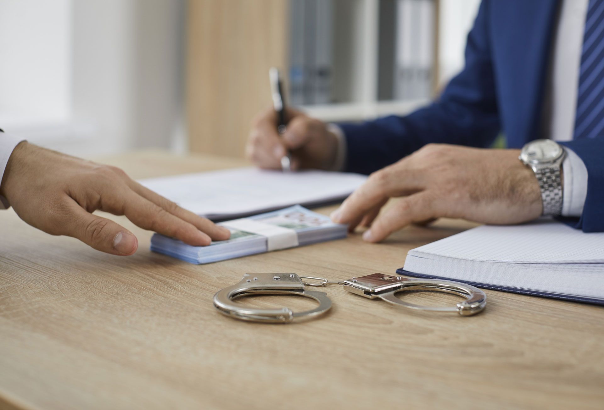 A man hands over cash to a bondsman in a suit, asking to release his friend on bail.