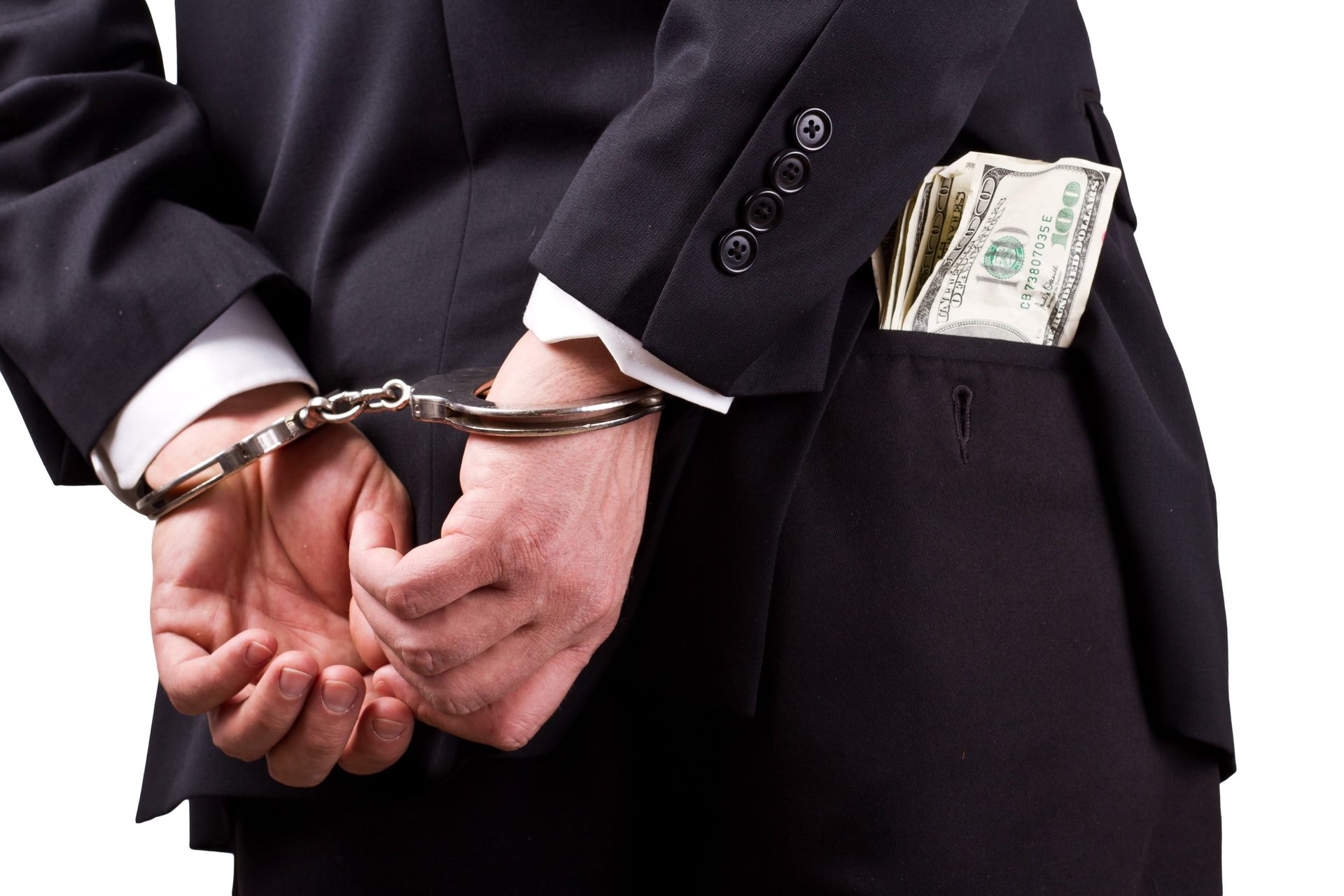 A man in a suit is handcuffed and has money in his pocket