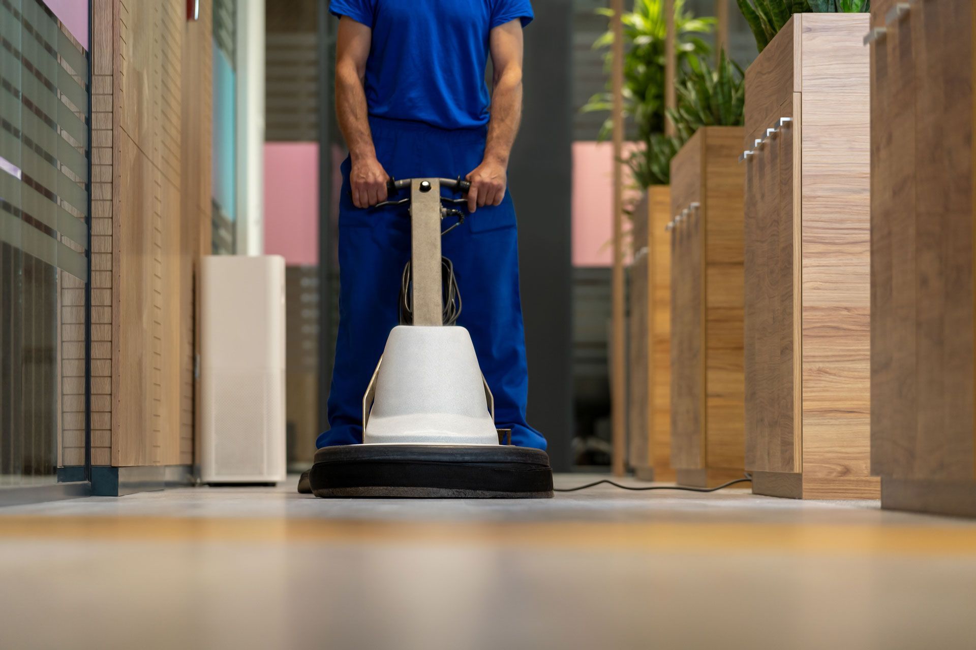 A man is cleaning the floor with a machine in an office.