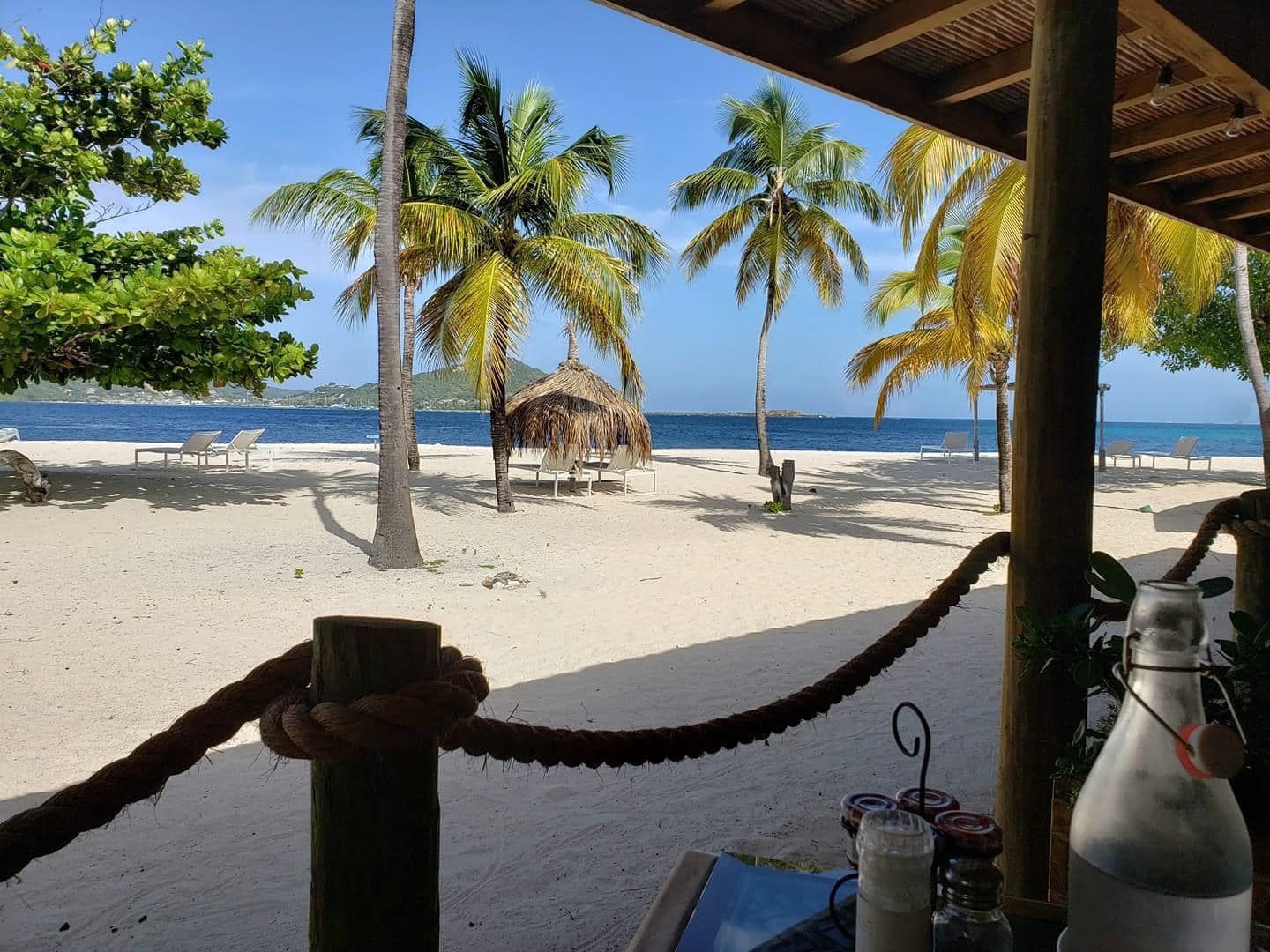 A bottle of water sits on a table in front of a beach