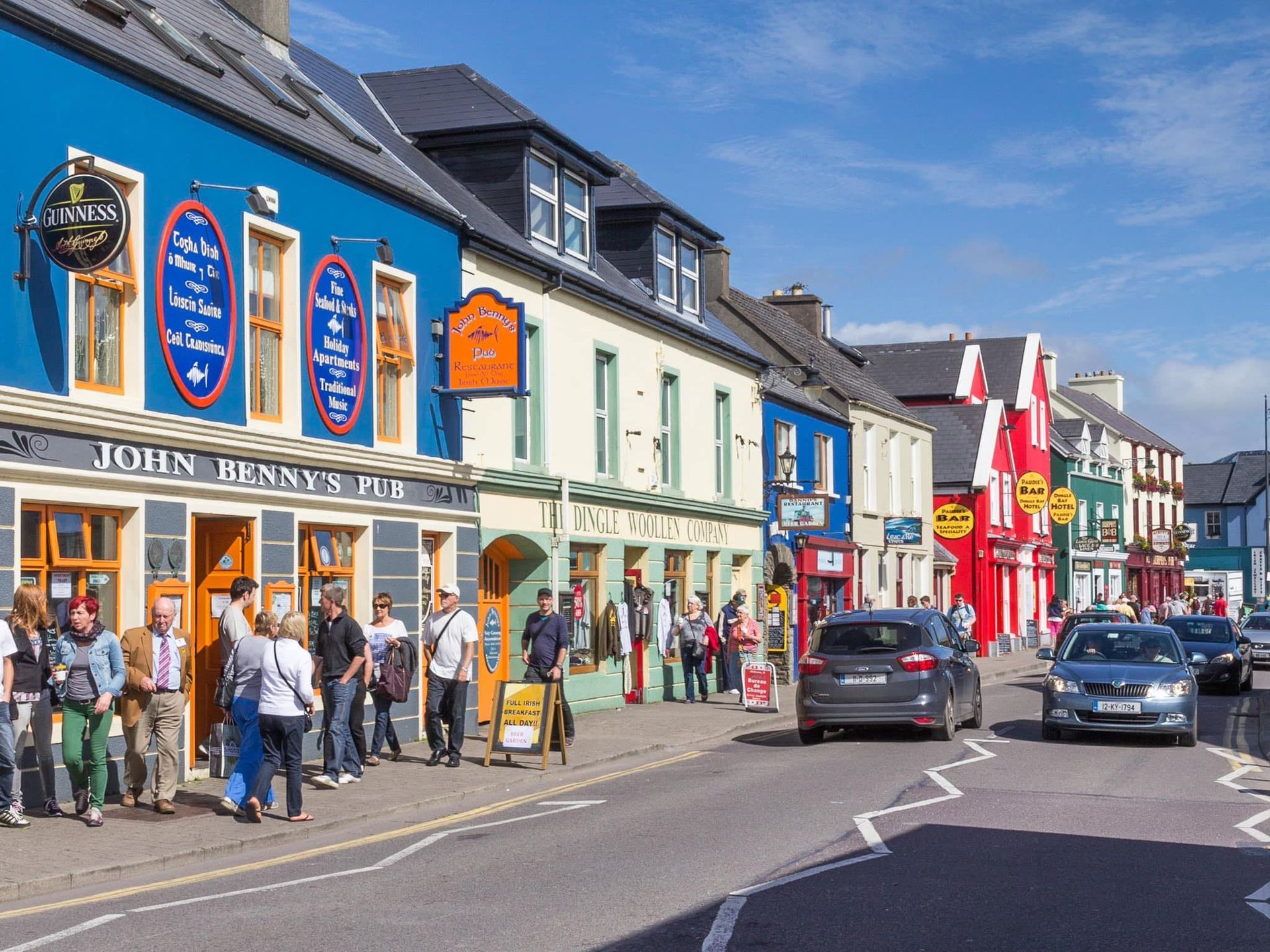 A group of people are standing in front of a row of colorful buildings.