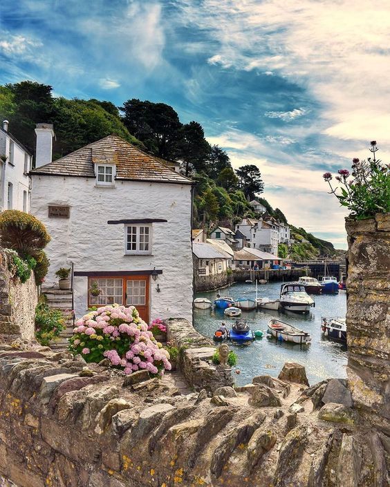 A small town with boats docked in the water and a stone wall surrounding it.