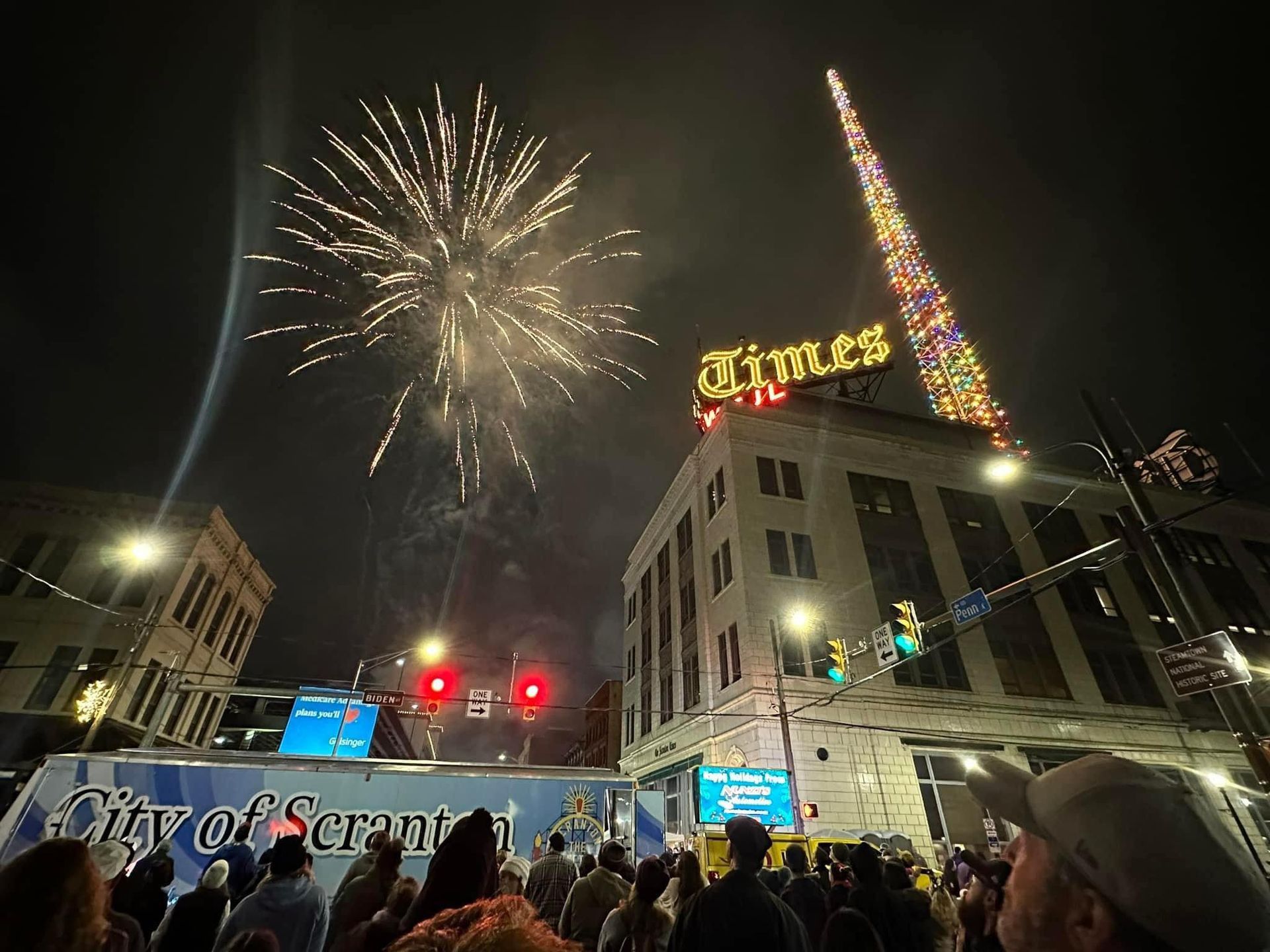 A crowd of people watching fireworks in front of a building that says times