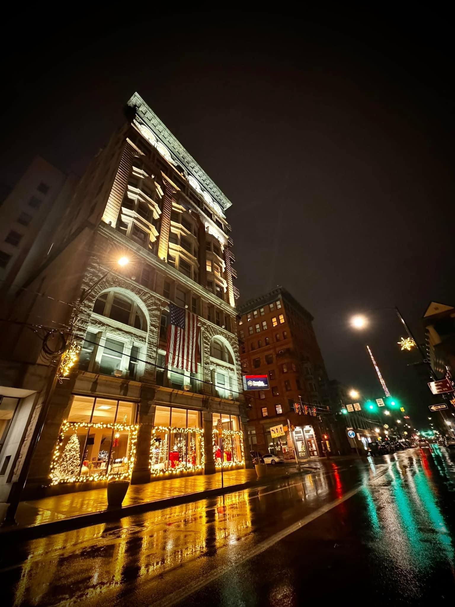 A building with christmas lights on it is lit up at night.