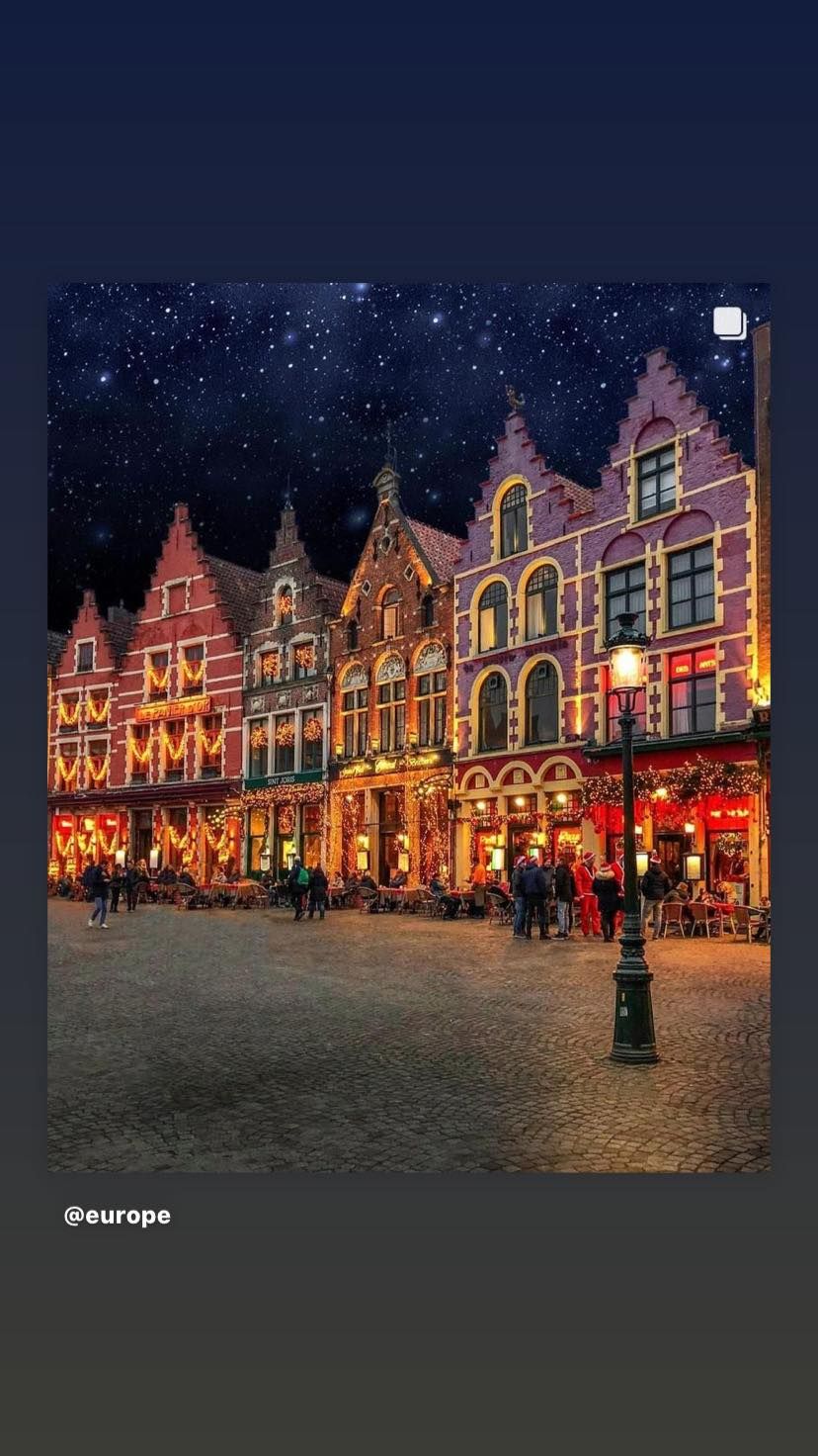 A group of buildings are lit up at night in a city square.
